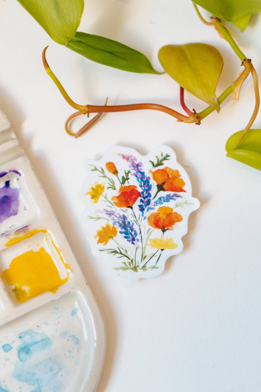 A white sticker of California poppies, California buttercups, and silver lupine.