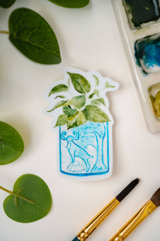 A sticker of a pothos plant in a blue and white porcelain vase, decorated with a goat.