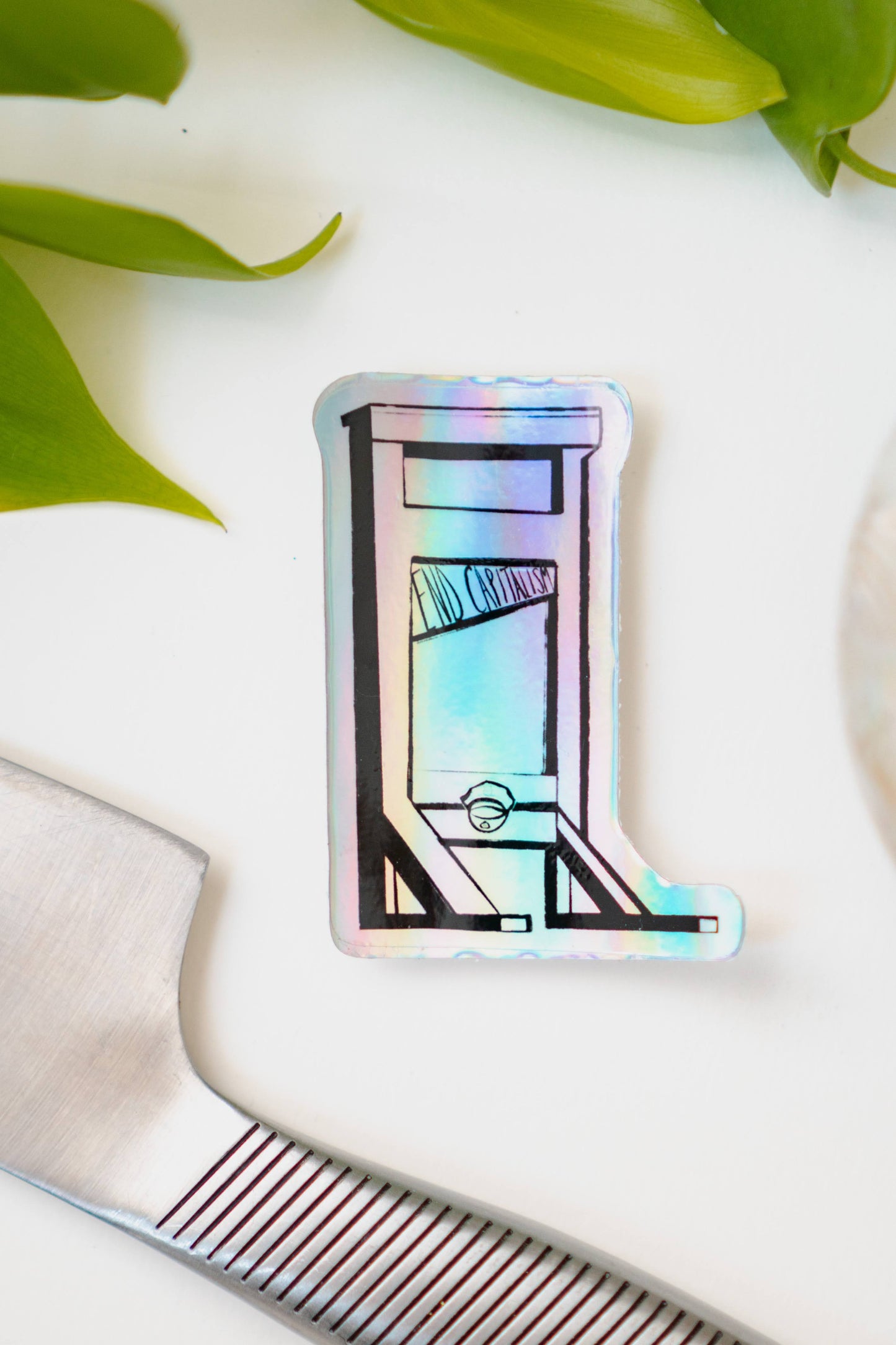 A holographic sticker of a guillotine, with the words "End Capitalism" written on the blade.