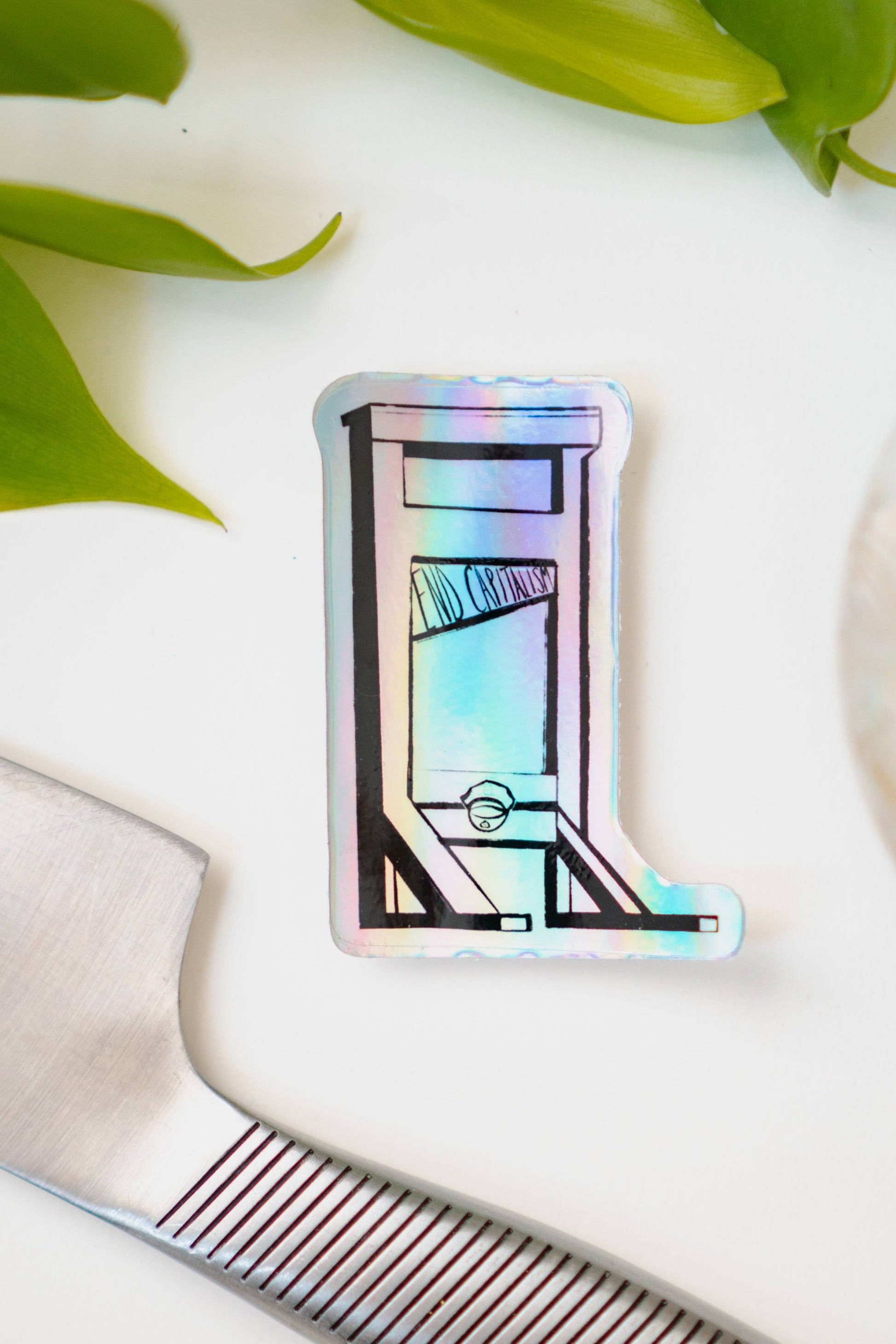 A holographic sticker of a guillotine, with the words "End Capitalism" written on the blade.