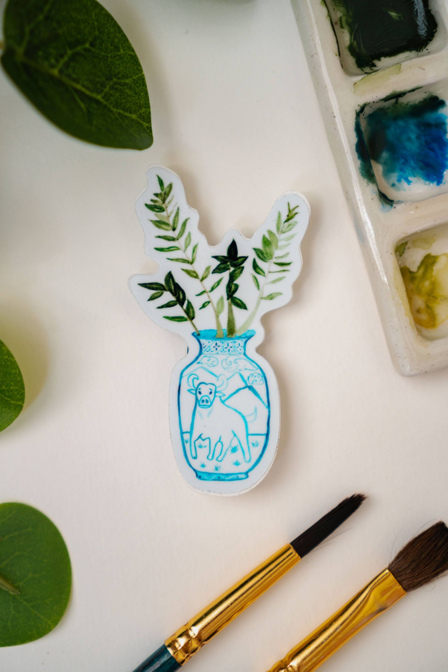 A sticker of a ZZ plant in a blue and white porcelain vase, decorated with an ox.