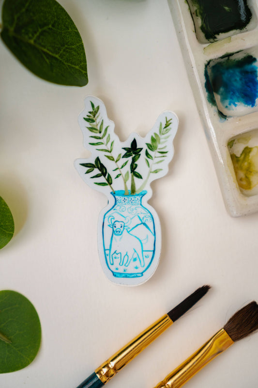 A sticker of a ZZ plant in a blue and white porcelain vase, decorated with an ox.