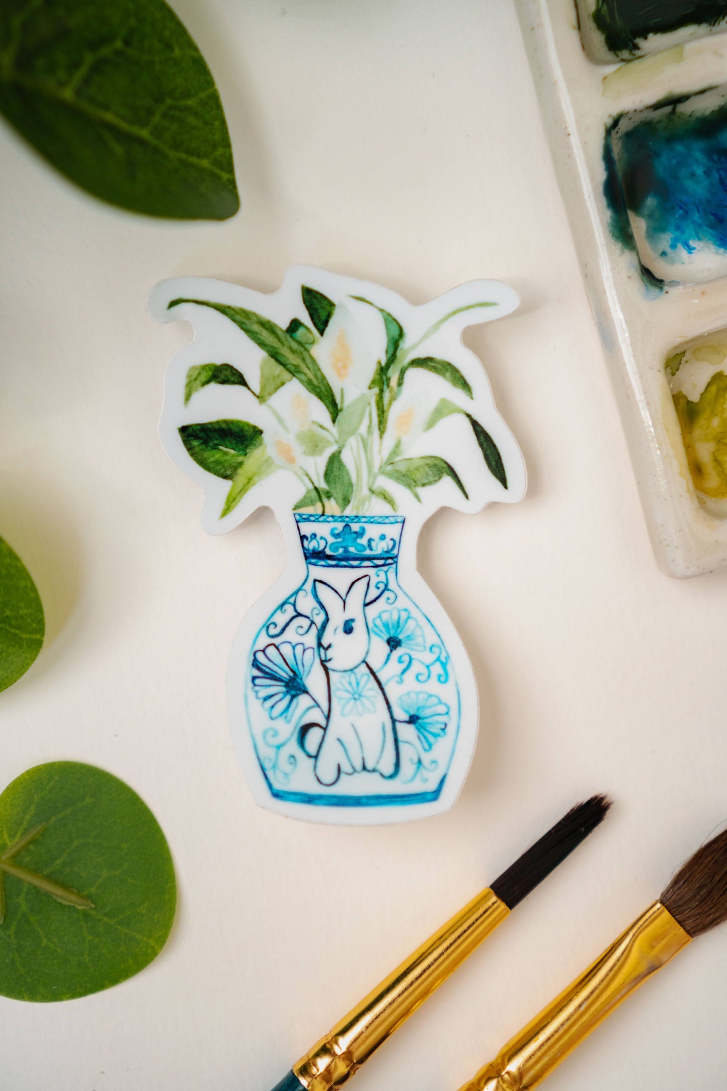 A sticker of a peace lily plant in a blue and white porcelain vase, decorated with a rabbit.