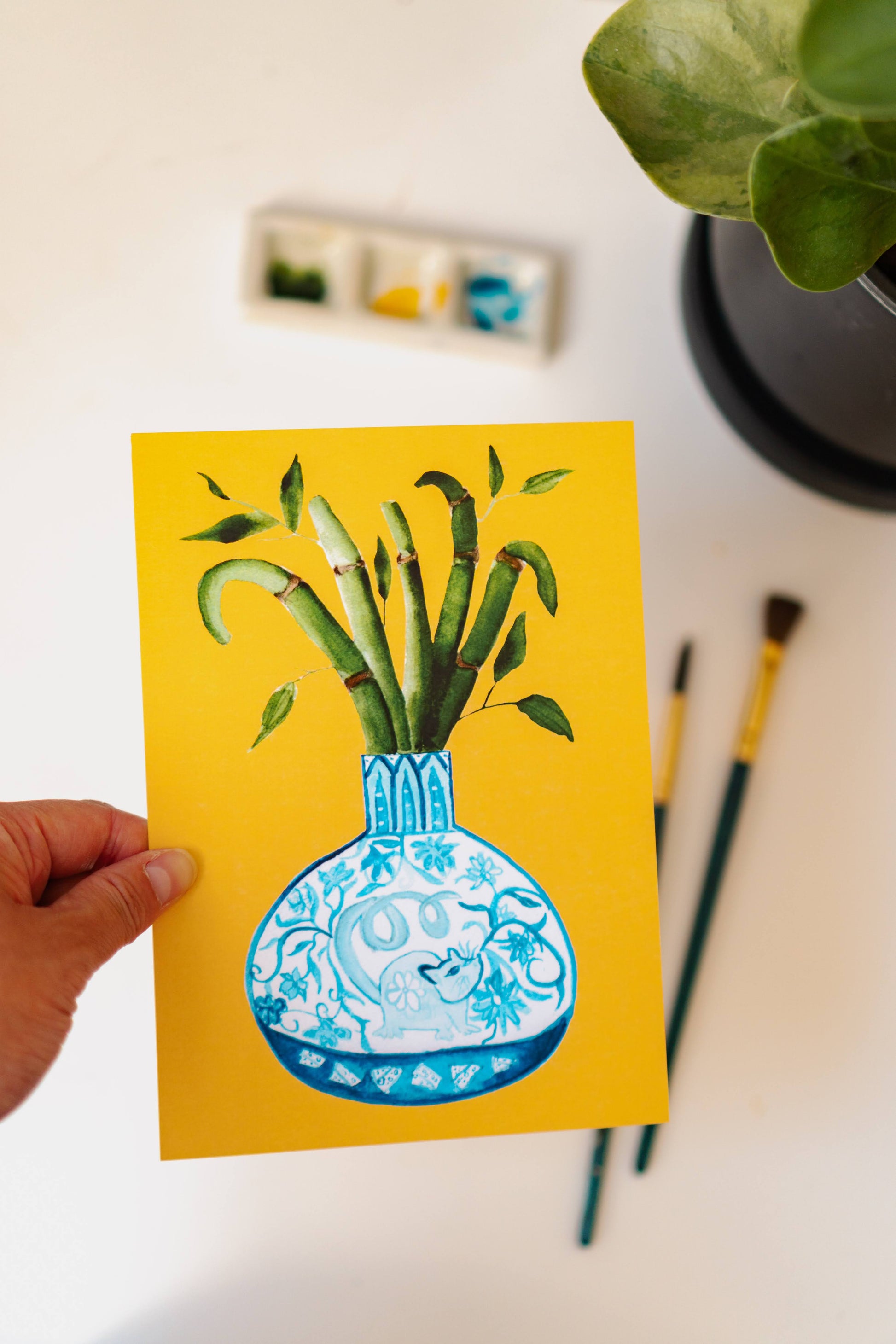 A print of a bamboo plant in a blue and white porcelain vase, decorated with a rat.