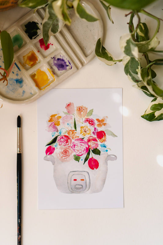 A pink, blue, and white print of a bouquet of tulips, roses, and other flowers sprouting out of a rice cooker.