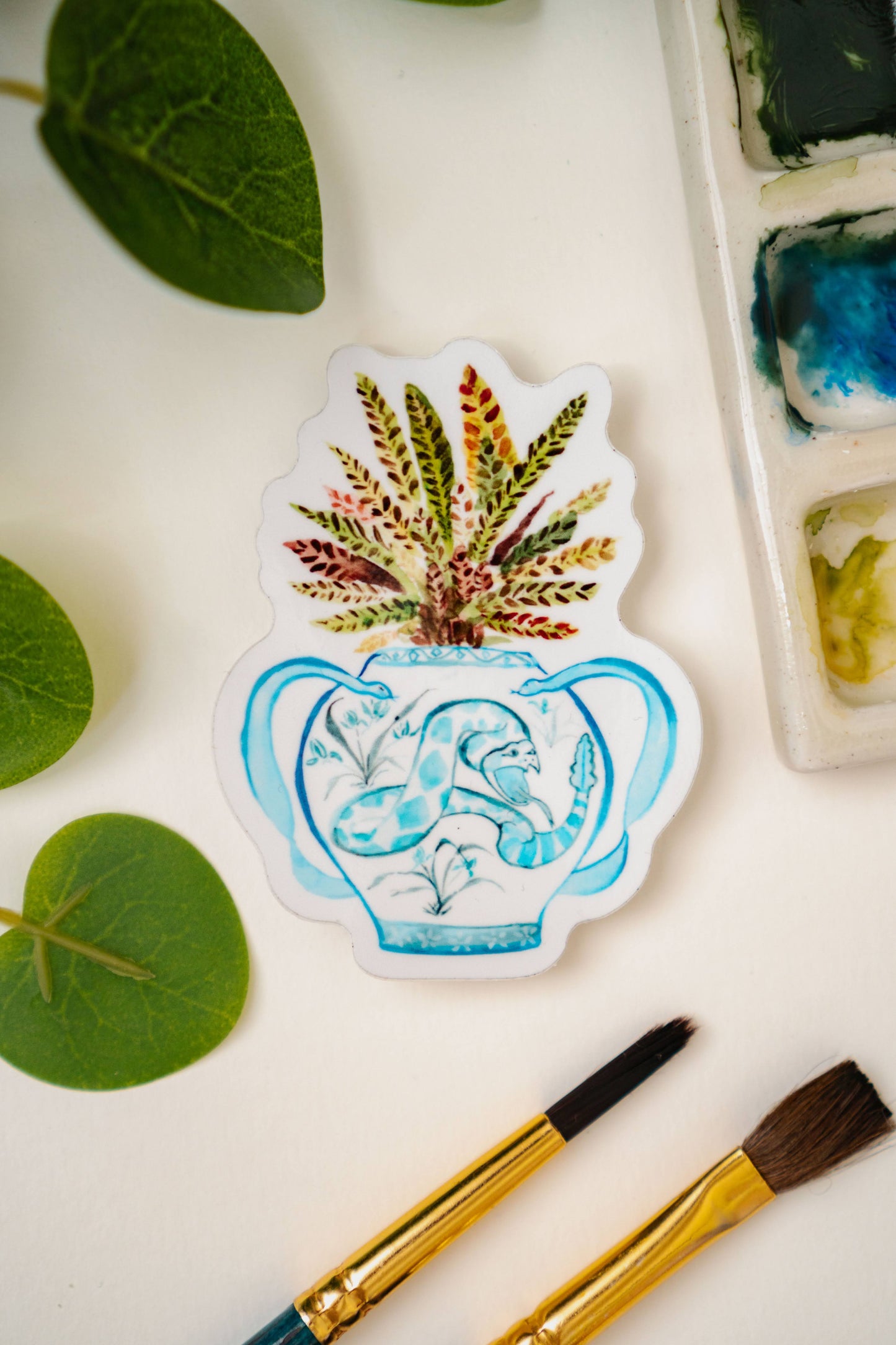 A print of a rattlesnake plant in a blue and white porcelain vase, decorated with a snake.