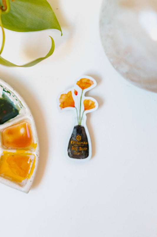 A white sticker of four orange California Poppies in a soy sauce bottle.
