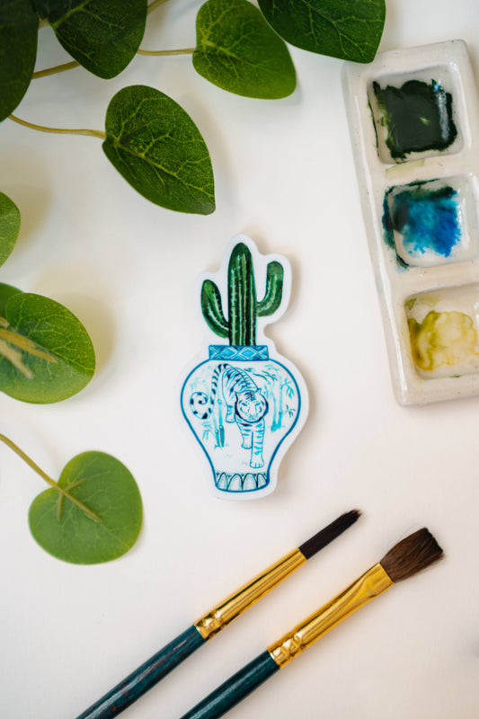 A sticker of a saguaro cactus in a blue and white porcelain vase, decorated with a tiger.