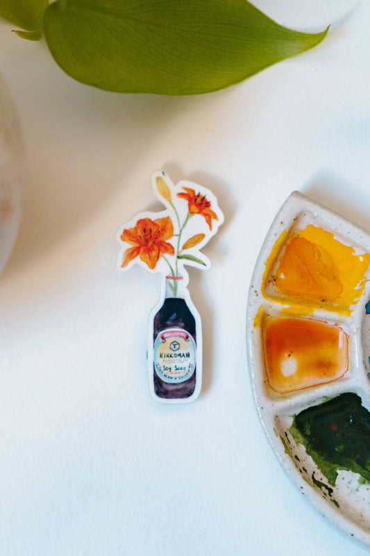 A watercolor sticker of two orange tiger lilies in a Kikkoman soy sauce bottle.