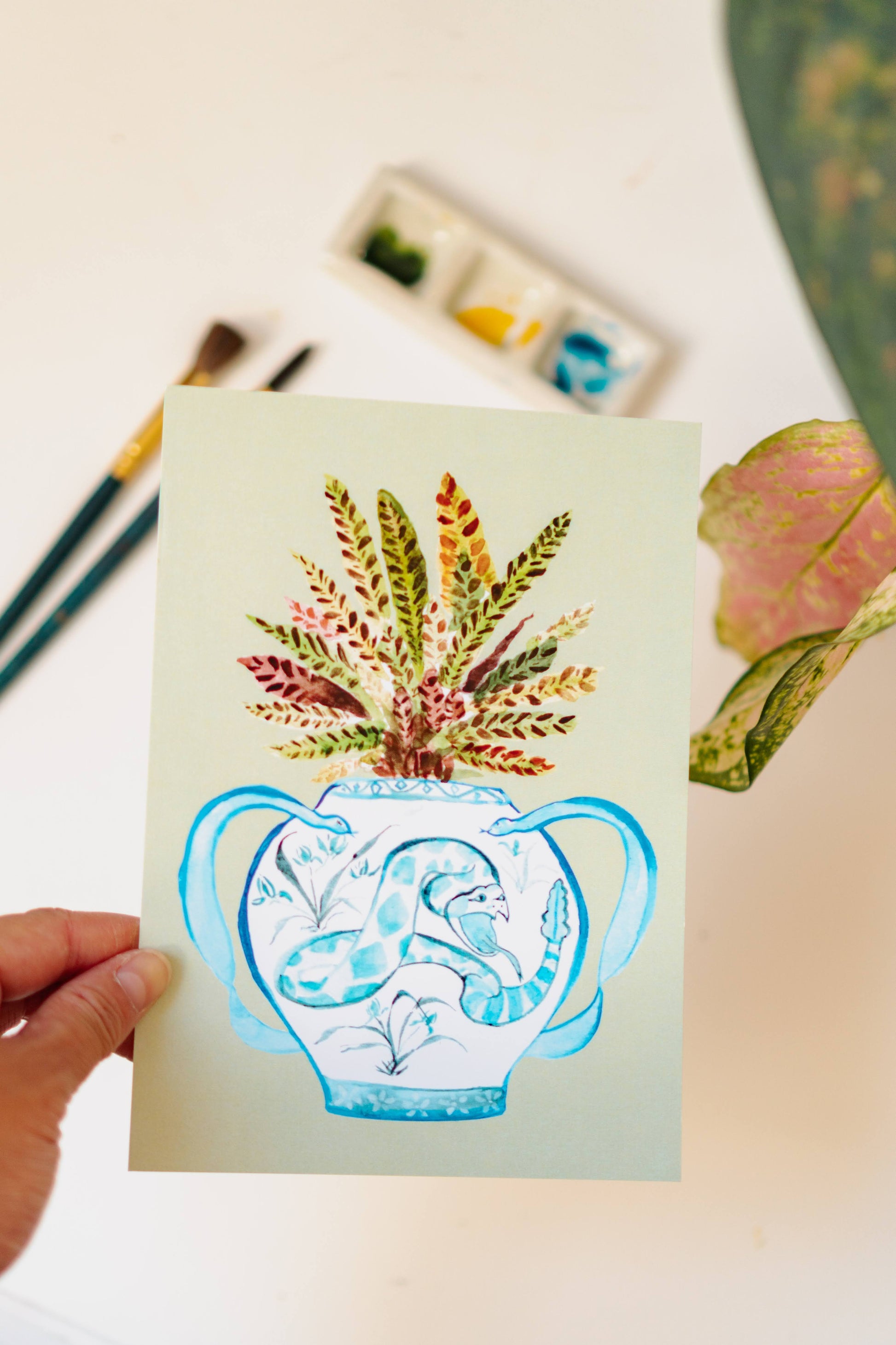 A print of a rattlesnake plant in a blue and white porcelain vase, decorated with a snake.