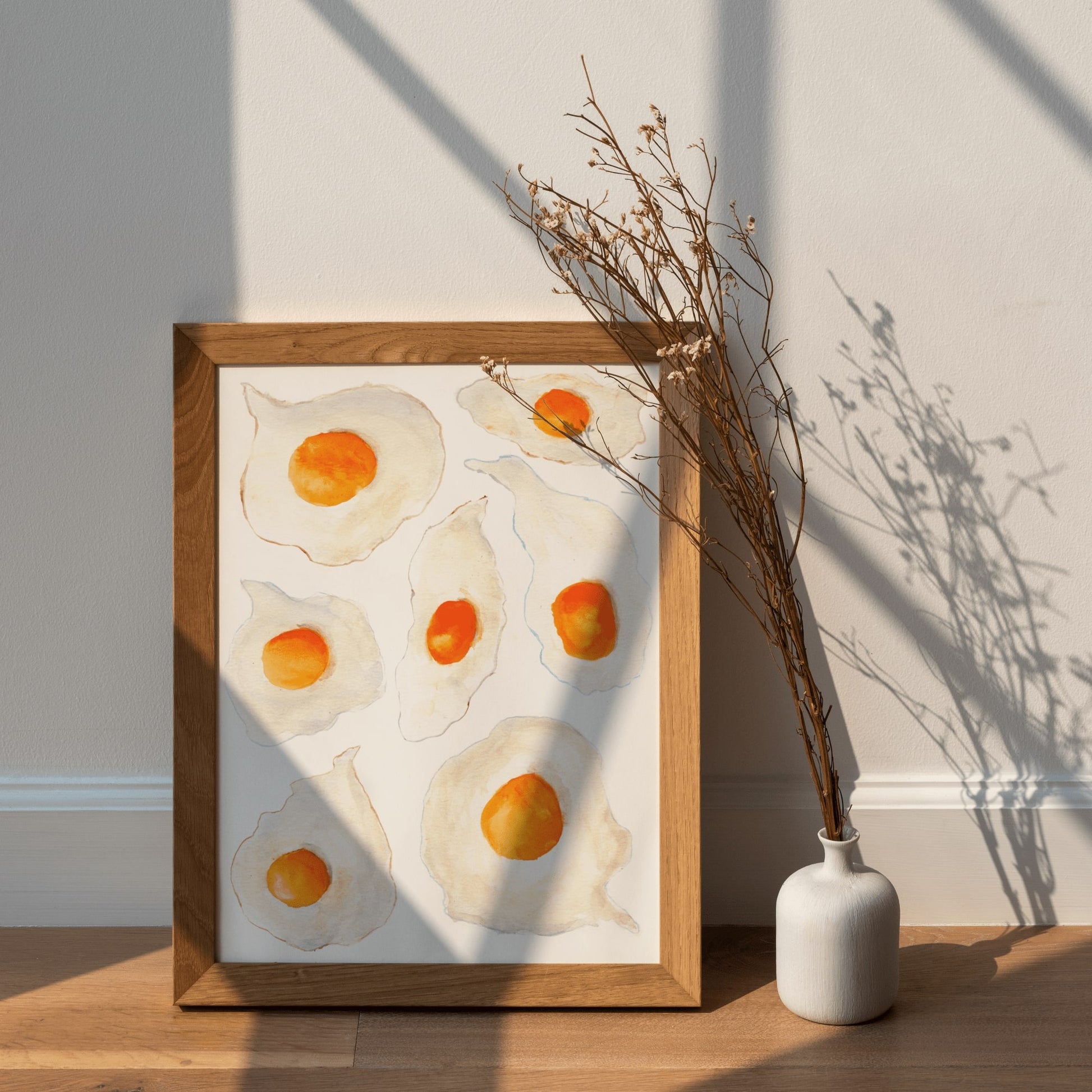 A watercolor print of seven sunny side up eggs with bright orange yorks and crispy colorful edges.