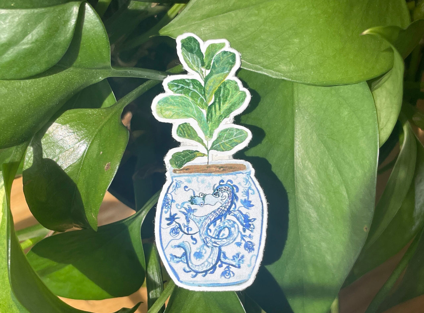 A sticker of a fiddle-leaf fig plant in a blue and white porcelain vase, decorated with a dragon.