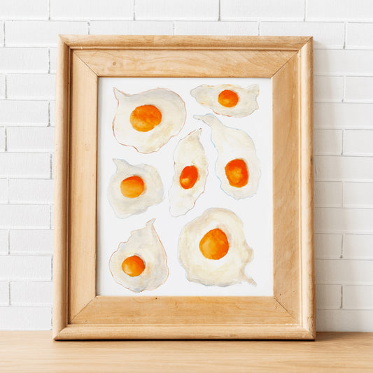 A watercolor print of seven sunny side up eggs with bright orange yorks and crispy colorful edges.