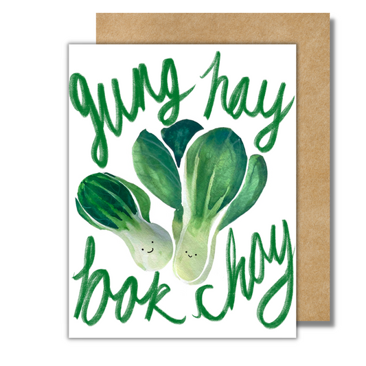 A white greeting card with a green bok choy and the words "gung hay bok choy" written in green cursive letters.