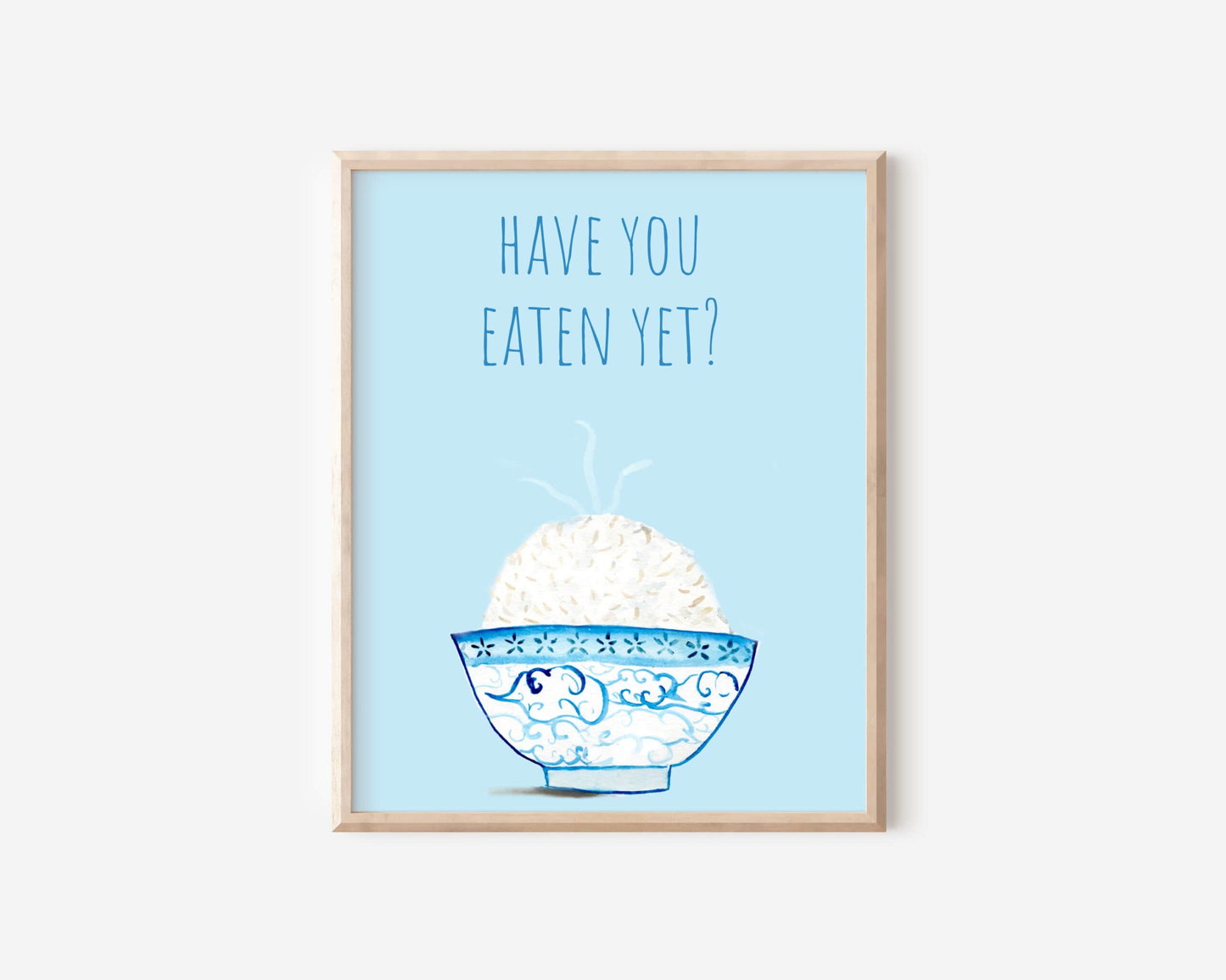 A light blue and white asian art print with the phrase, "Have you eaten yet?" written across the top. A steaming bowl of rice in a white and blue decorated bowl rests at the bottom of the print.