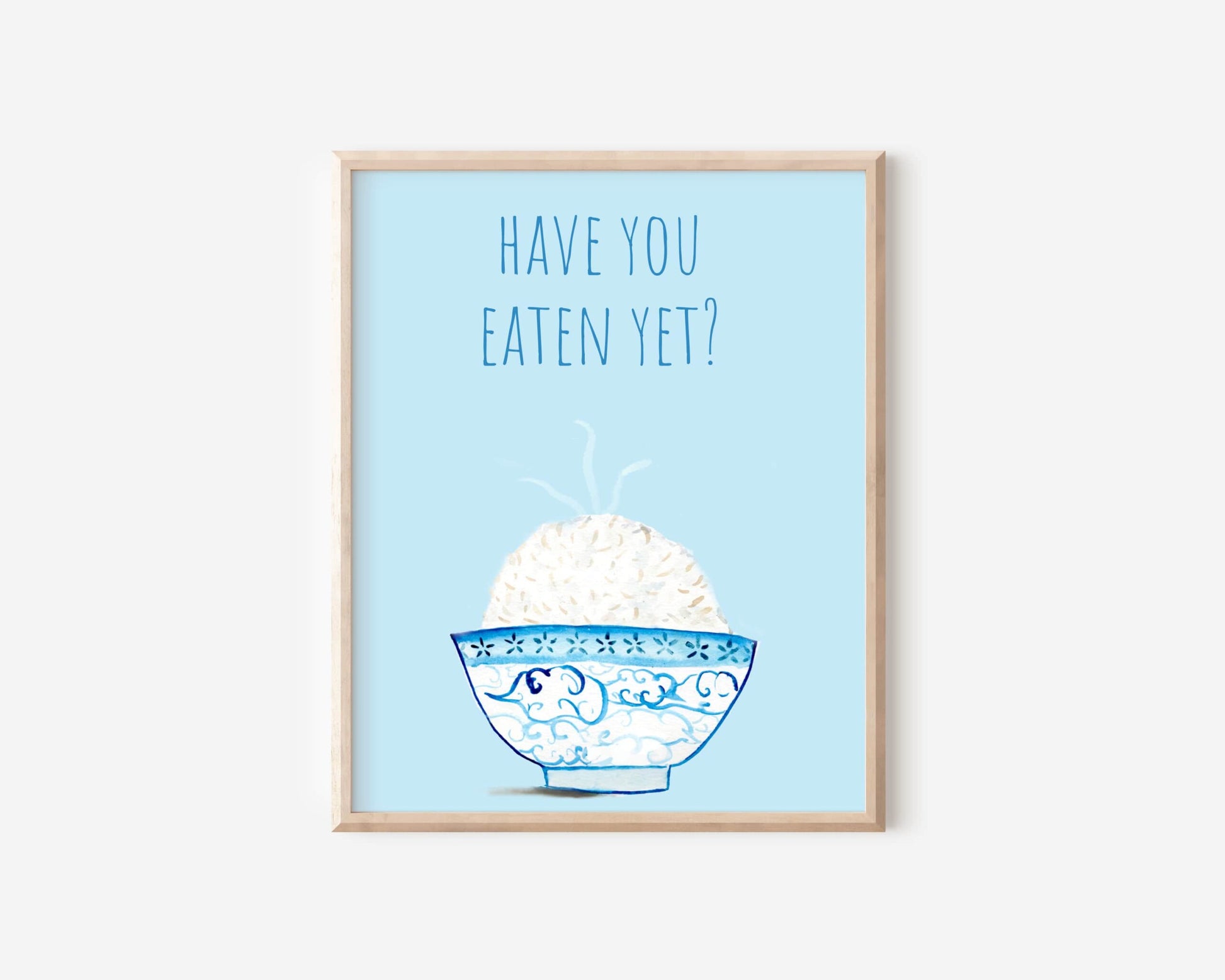 A light blue and white asian art print with the phrase, "Have you eaten yet?" written across the top. A steaming bowl of rice in a white and blue decorated bowl rests at the bottom of the print.