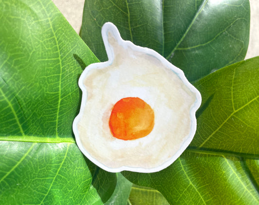A sticker of a round, sunny side up fried egg with a cheery orange yolk.