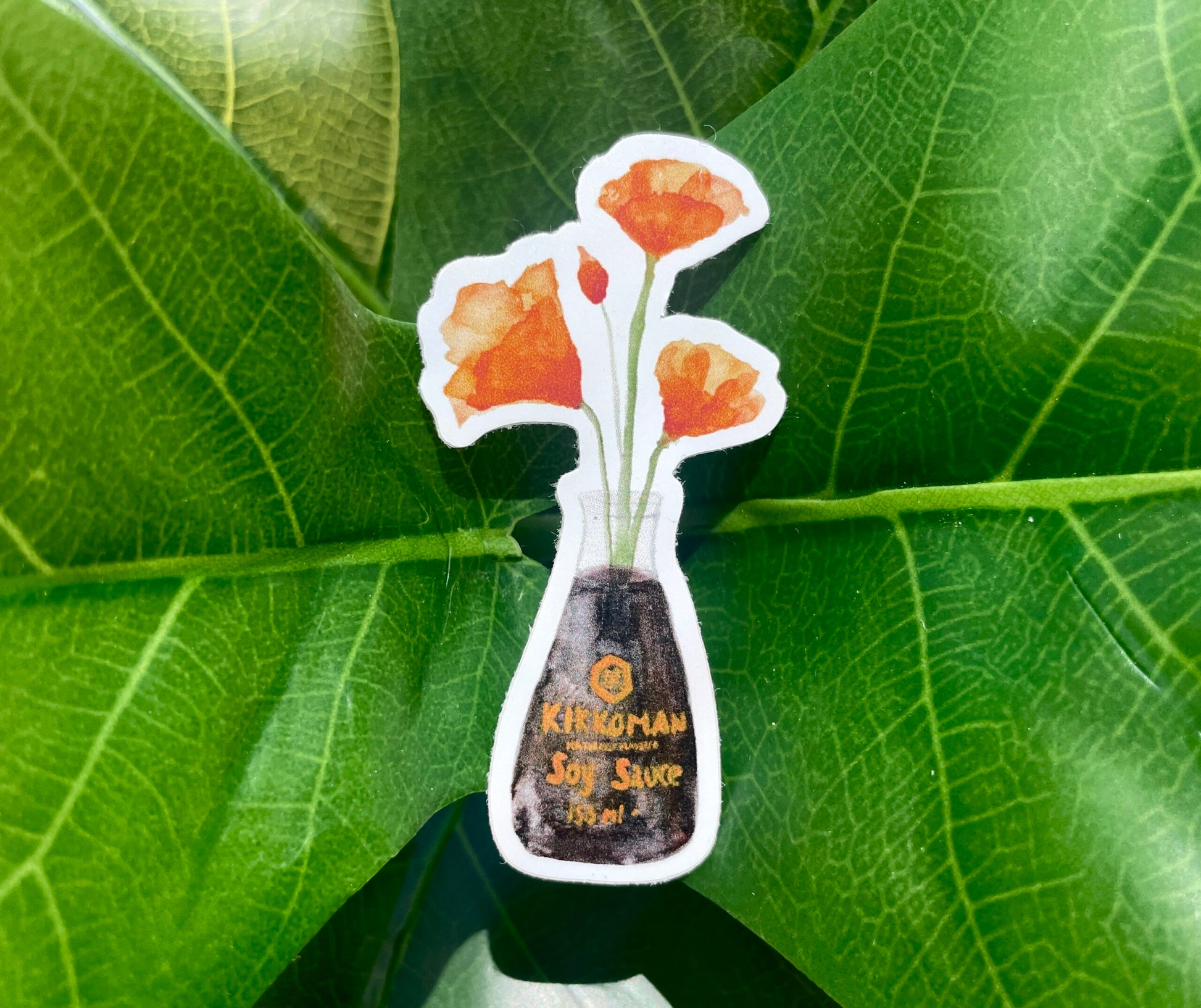 A white sticker of four orange California Poppies in a soy sauce bottle.
