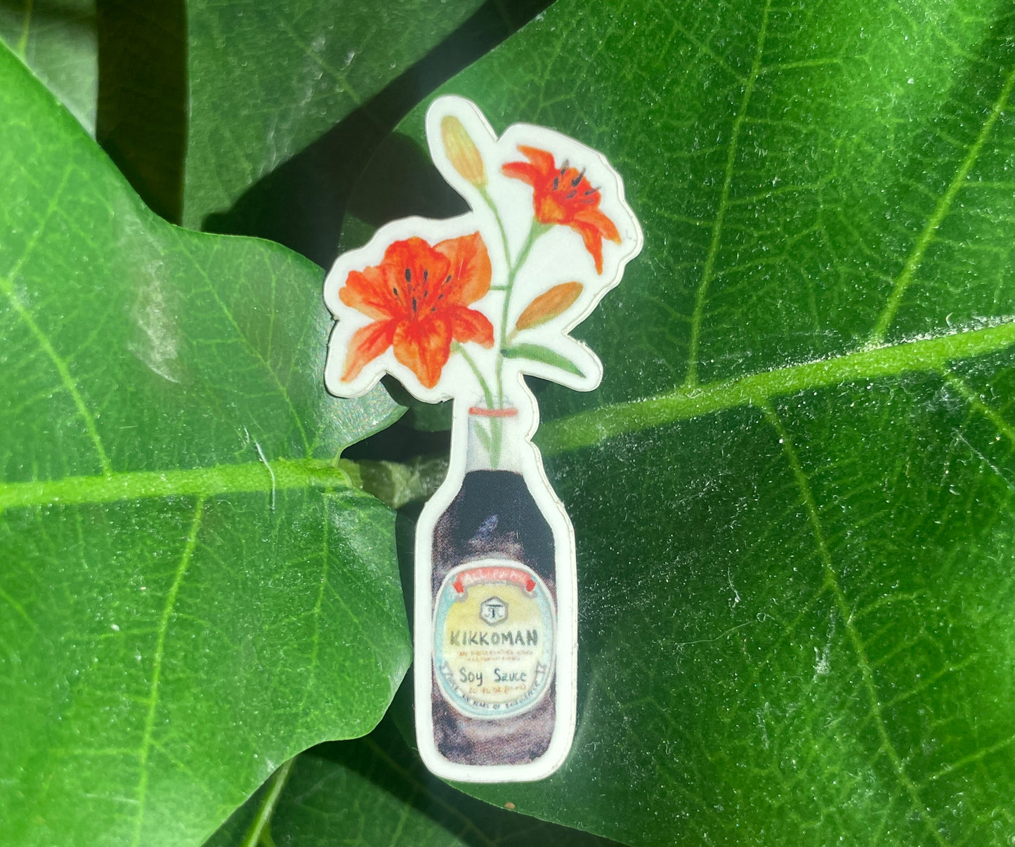 A watercolor sticker of two orange tiger lilies in a Kikkoman soy sauce bottle.