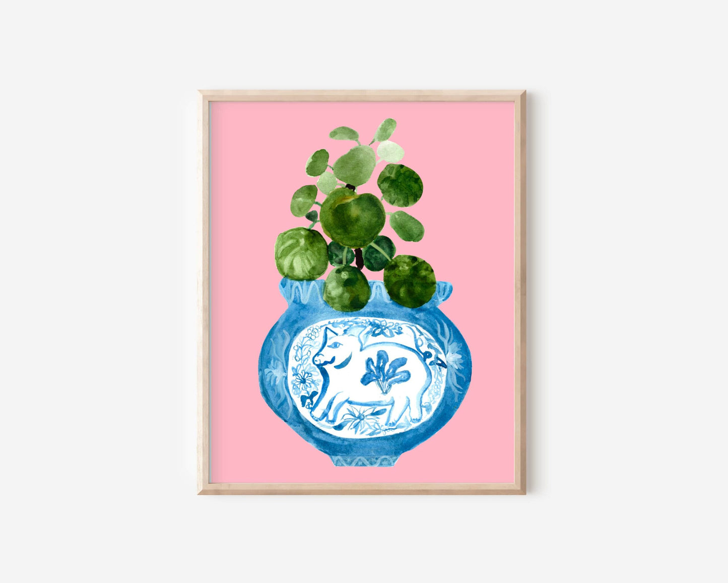 A print of a pilea plant in a blue and white porcelain vase, decorated with a pig.