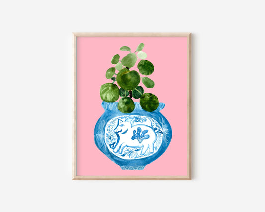 A print of a pilea plant in a blue and white porcelain vase, decorated with a pig.