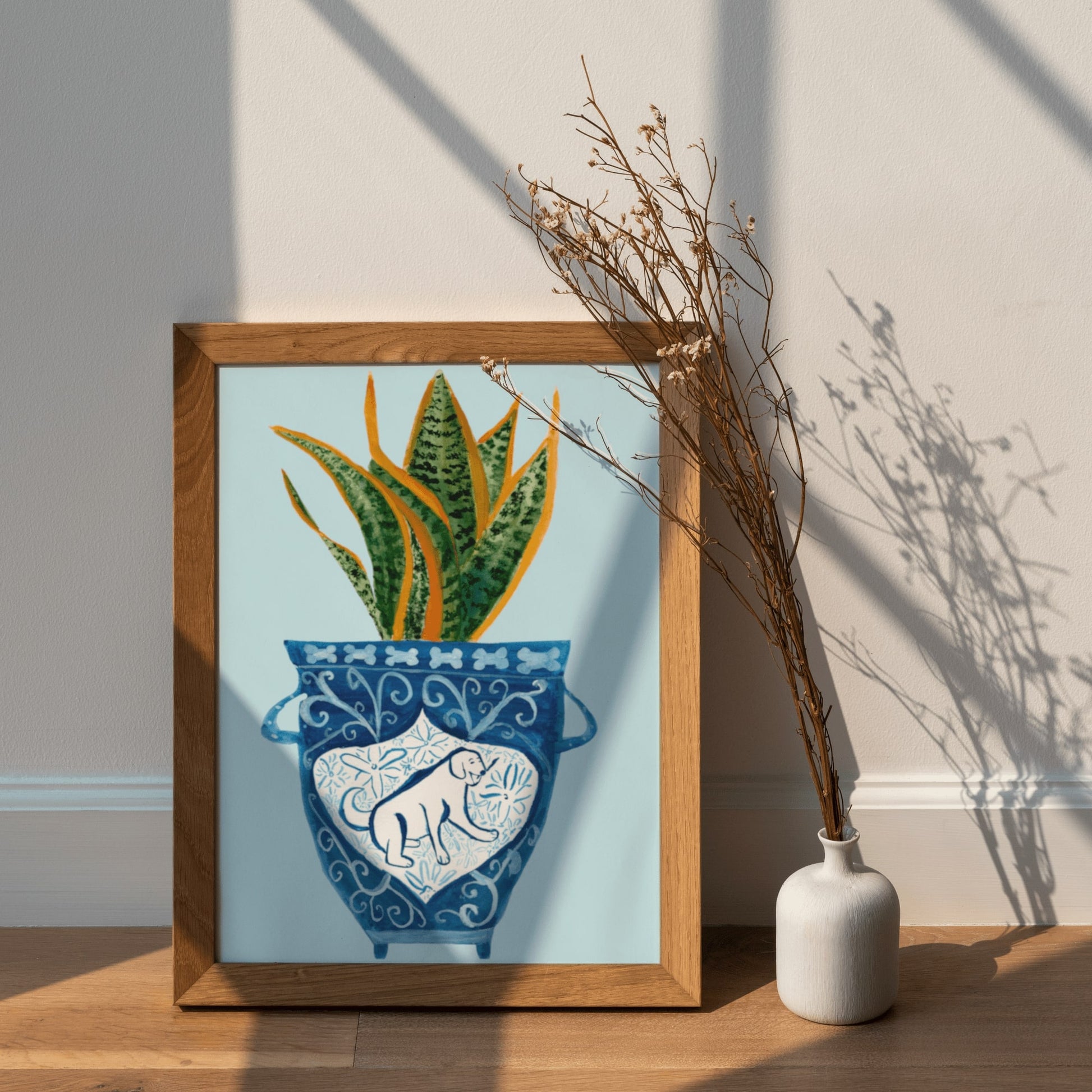 A print of a snake plant in a blue and white porcelain vase, decorated with a dog.