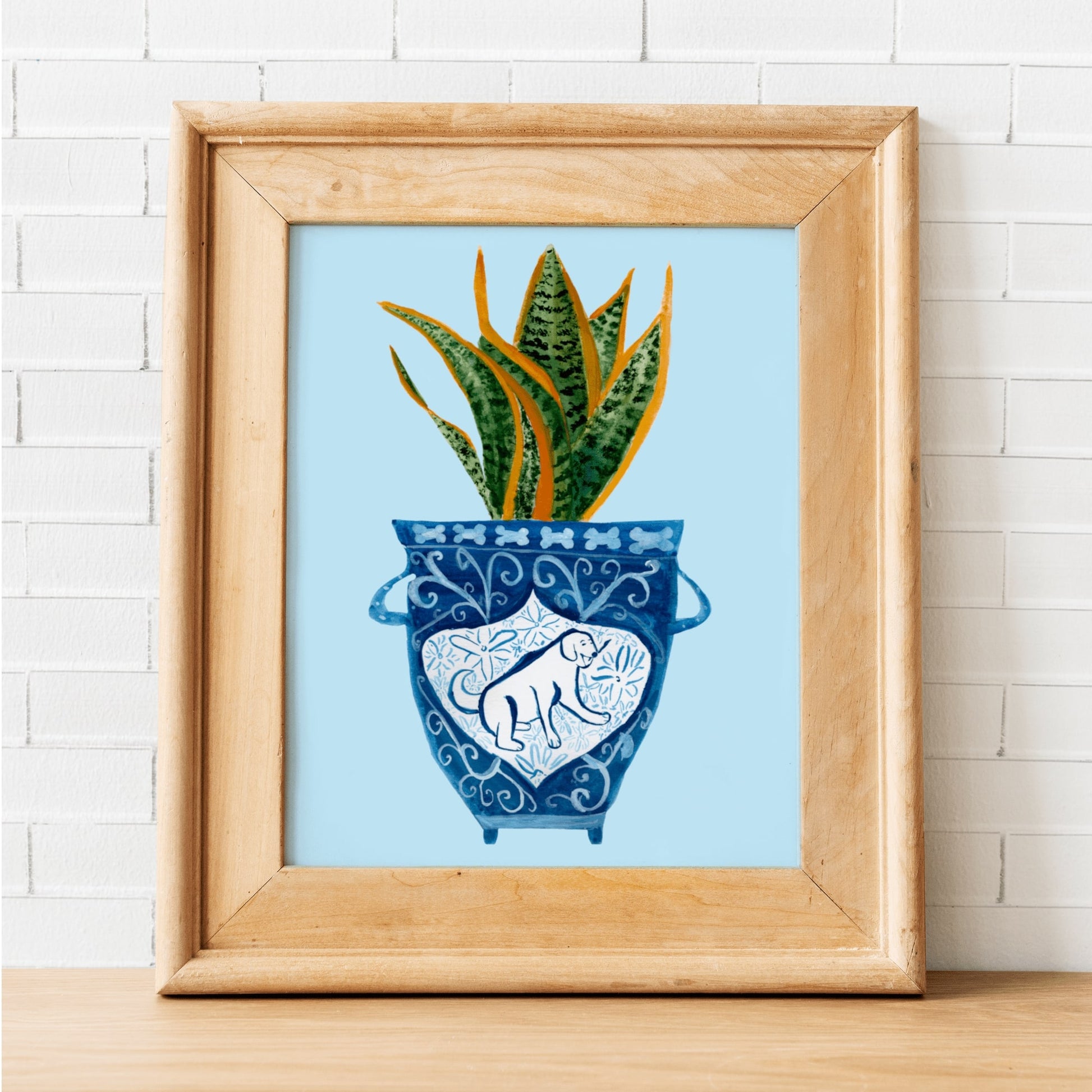 A print of a snake plant in a blue and white porcelain vase, decorated with a dog.