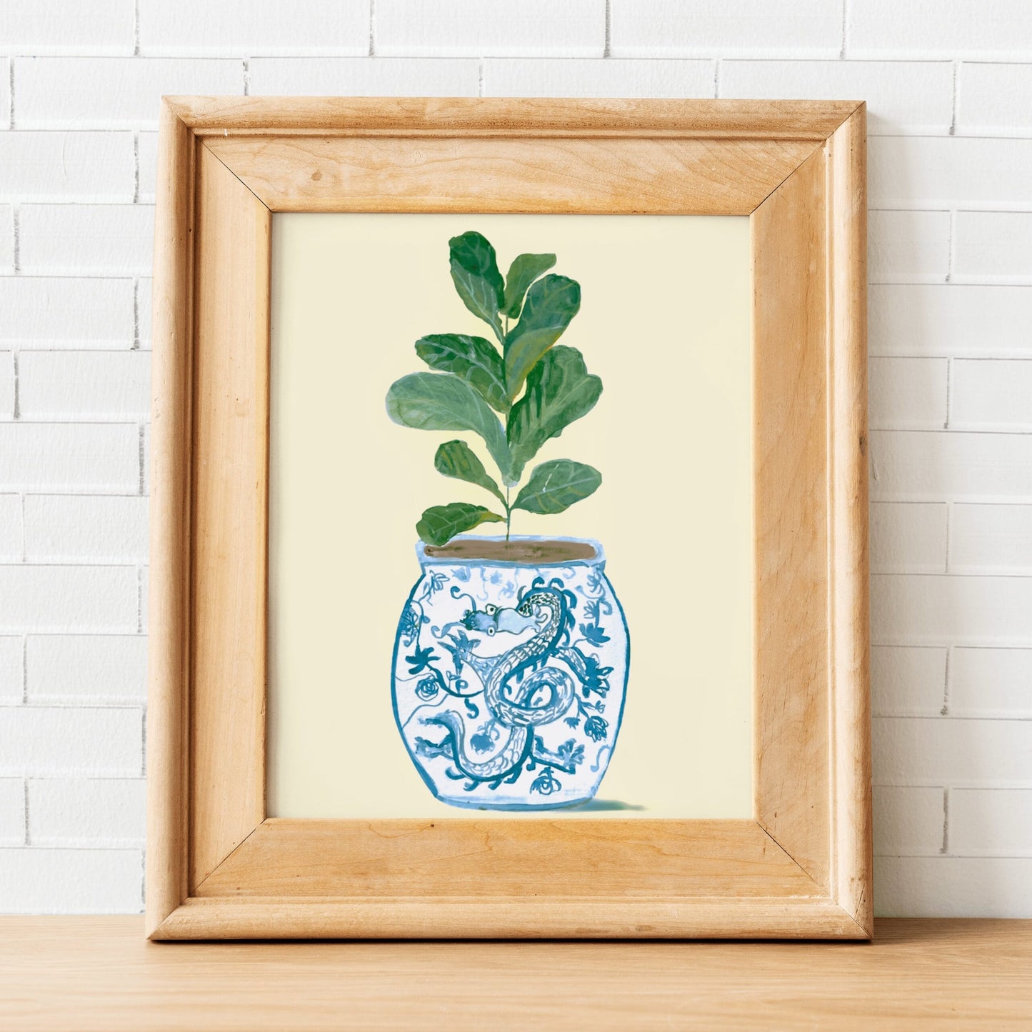 A print of a fiddle-leaf fig plant in a blue and white porcelain vase, decorated with a dragon.