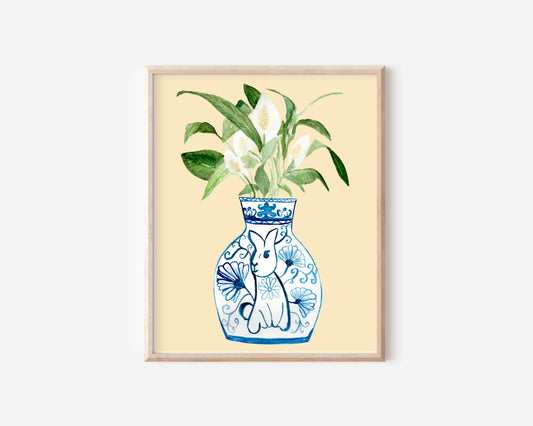 A print of a peace lily plant in a blue and white porcelain vase, decorated with a rabbit.