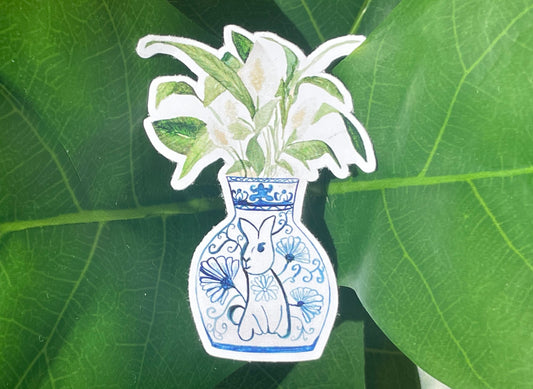 A sticker of a peace lily plant in a blue and white porcelain vase, decorated with a rabbit.
