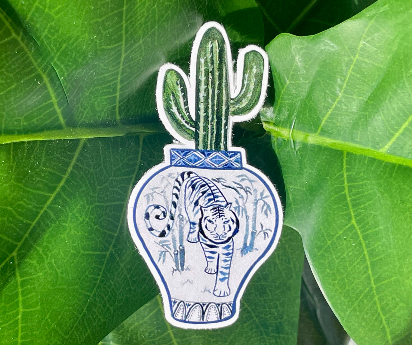A sticker of a saguaro cactus in a blue and white porcelain vase, decorated with a tiger.