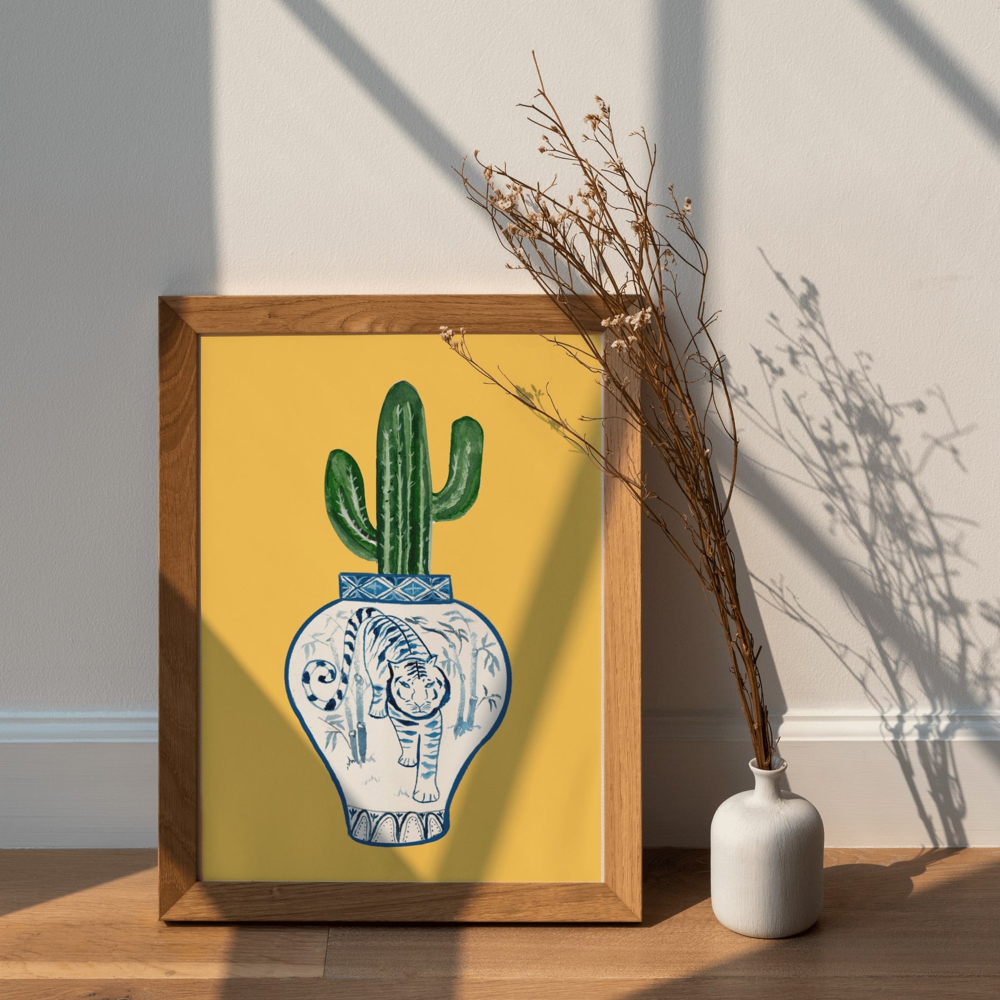 A print of a saguaro cactus in a blue and white porcelain vase, decorated with a tiger.
