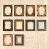 Nine empty ornate picture frames in various shapes and colors, arranged in a grid on a vintage beige damask wallpaper background.