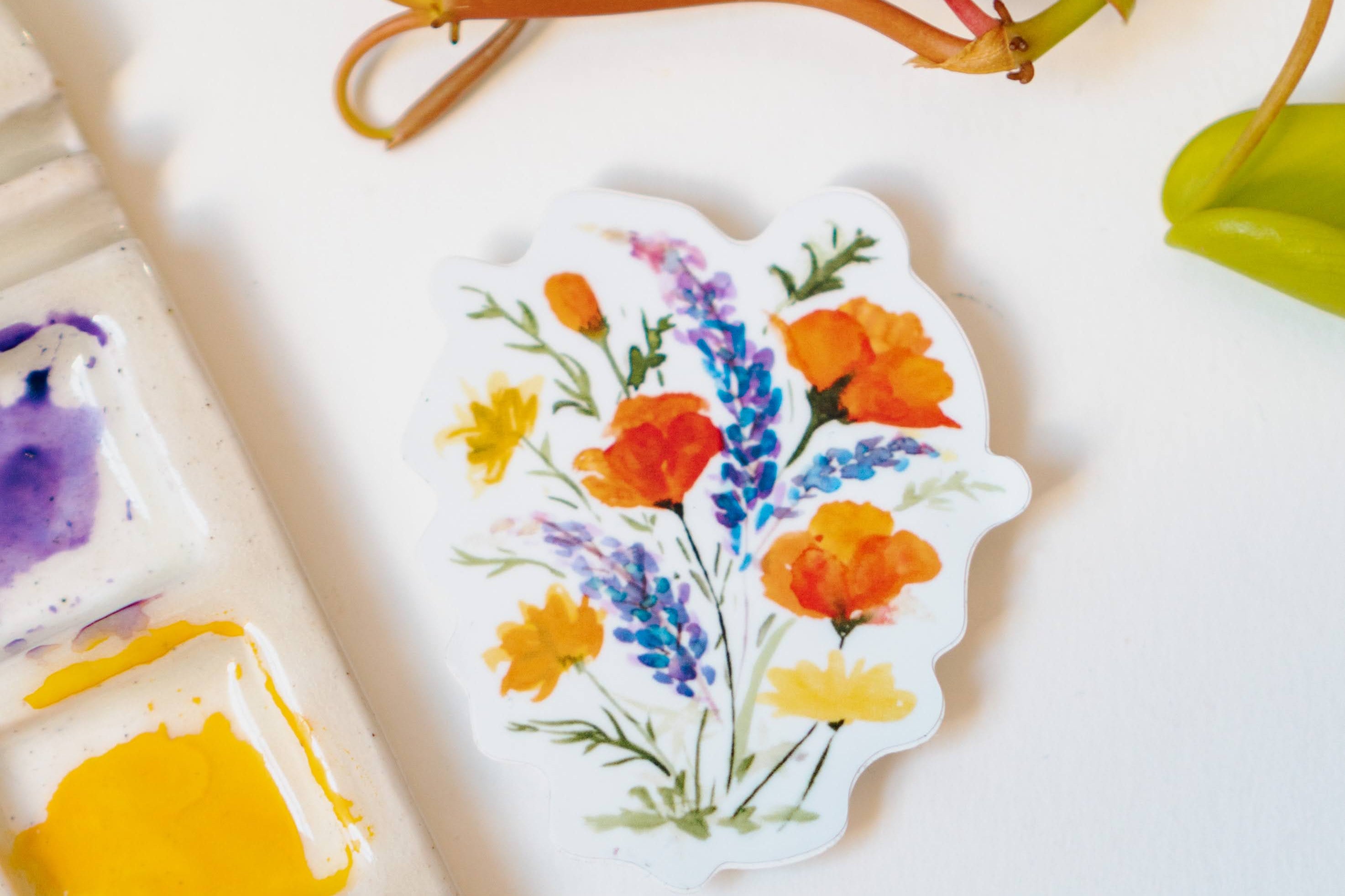 A white sticker of California poppies, California buttercups, and silver lupine.
