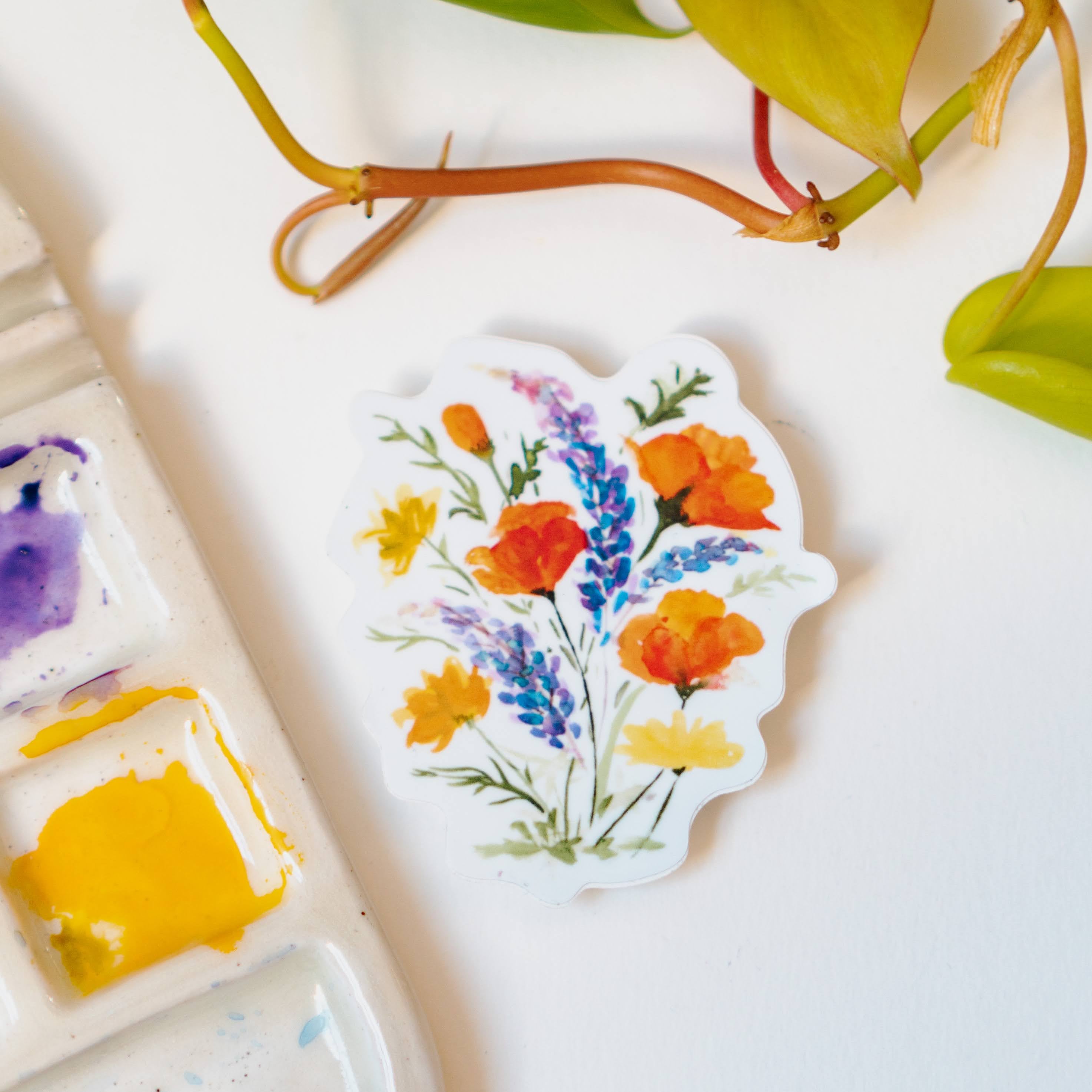 A white sticker of California poppies, California buttercups, and silver lupine.