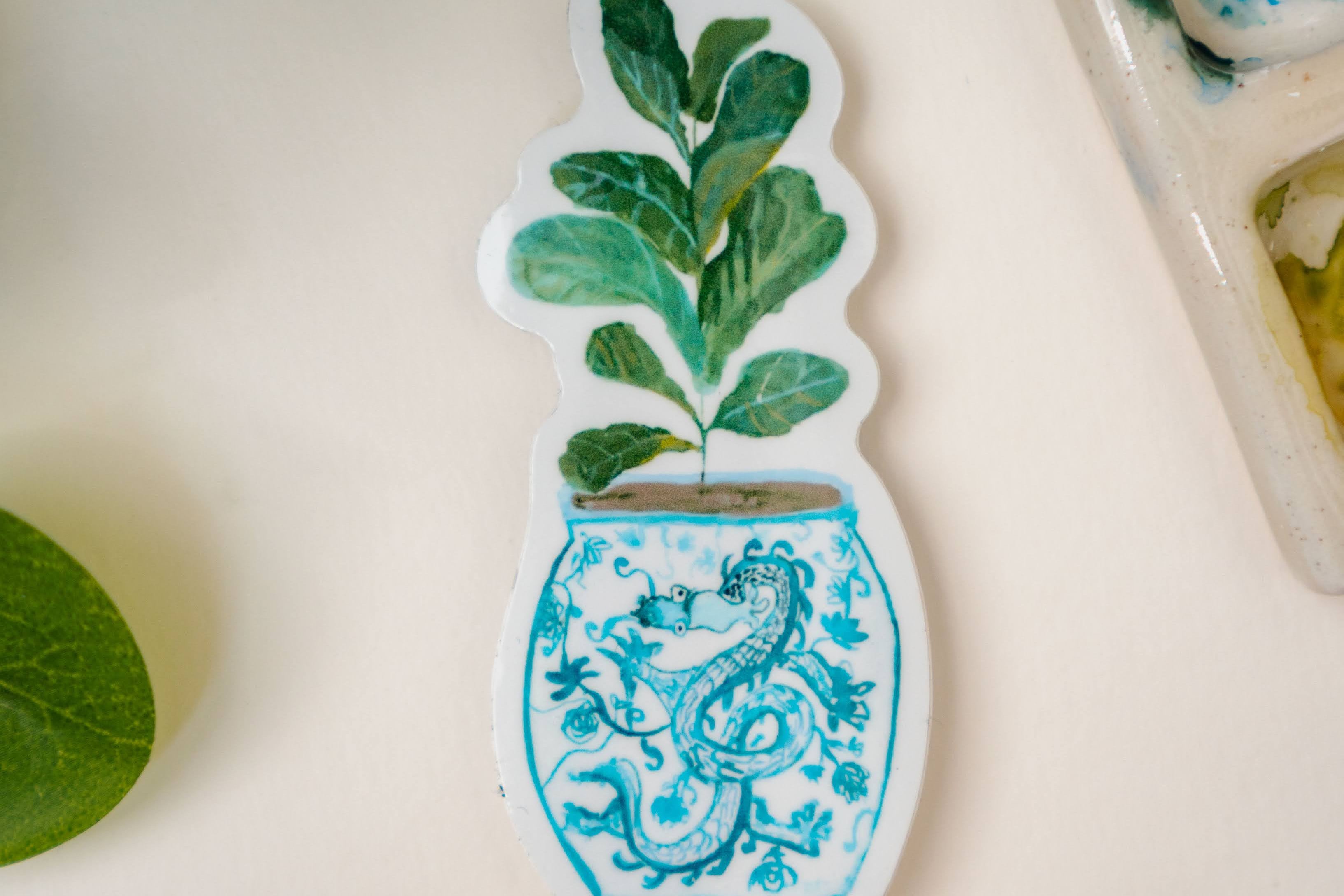 A sticker of a fiddle-leaf fig plant in a blue and white porcelain vase, decorated with a dragon.