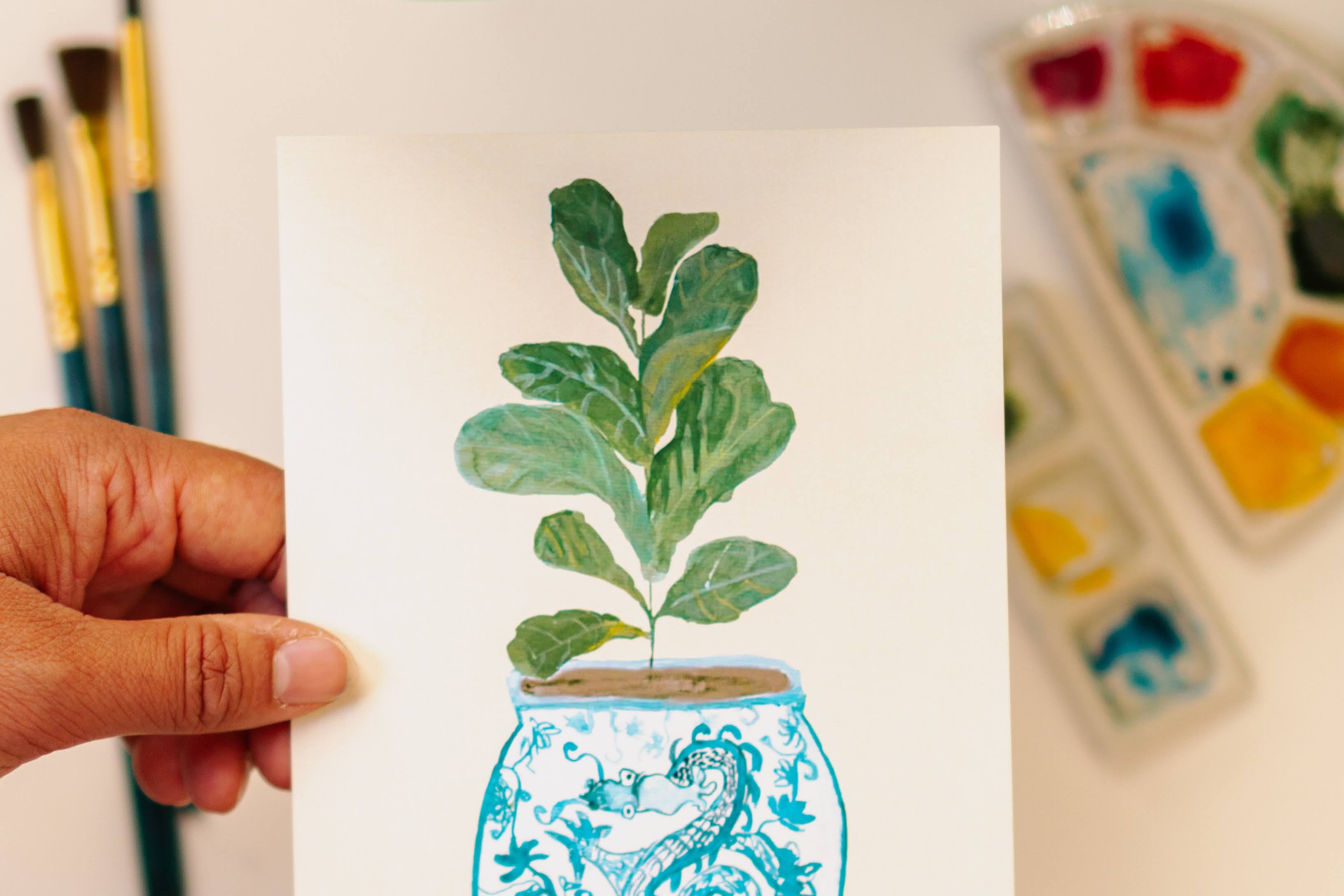 A print of a fiddle-leaf fig plant in a blue and white porcelain vase, decorated with a dragon.