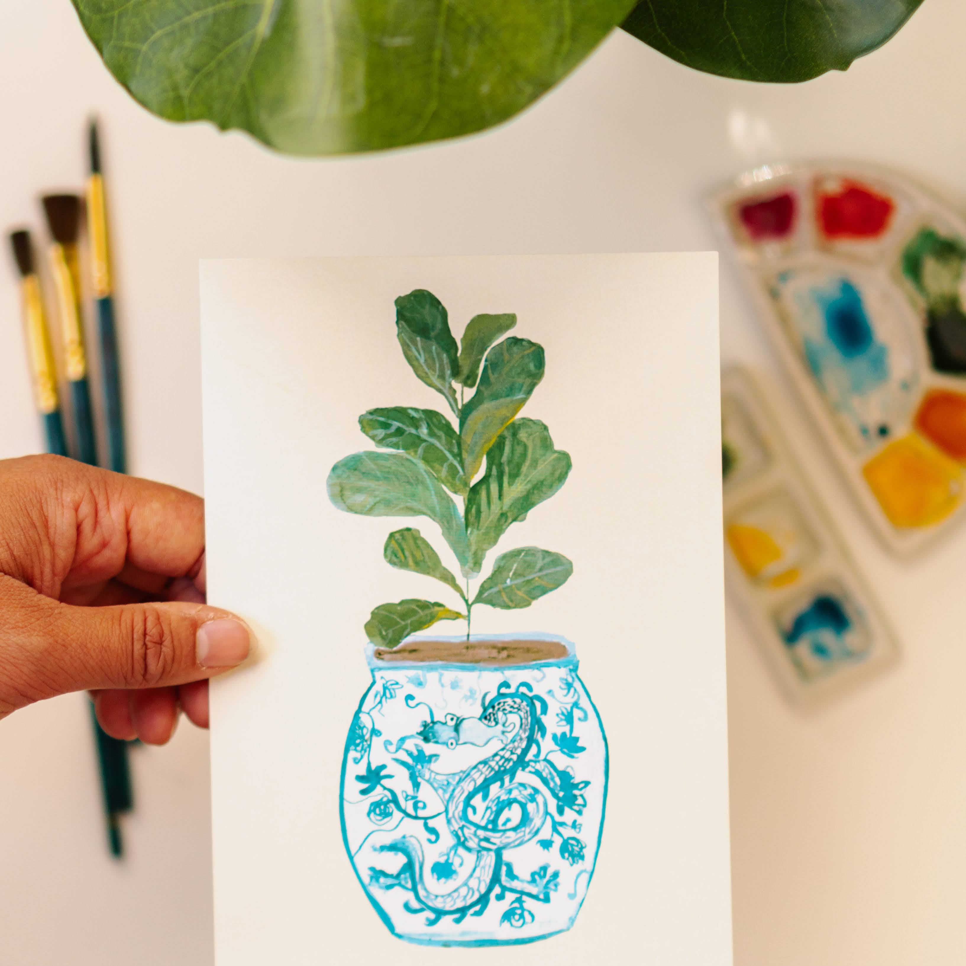 A print of a fiddle-leaf fig plant in a blue and white porcelain vase, decorated with a dragon.