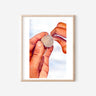 A watercolor print of two hands folding a pleated dumpling and finishing it with a twist.