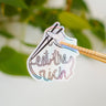 A holographic sticker featuring someone with a pair of chopsticks picking up a noodle which spells, "eat the rich."