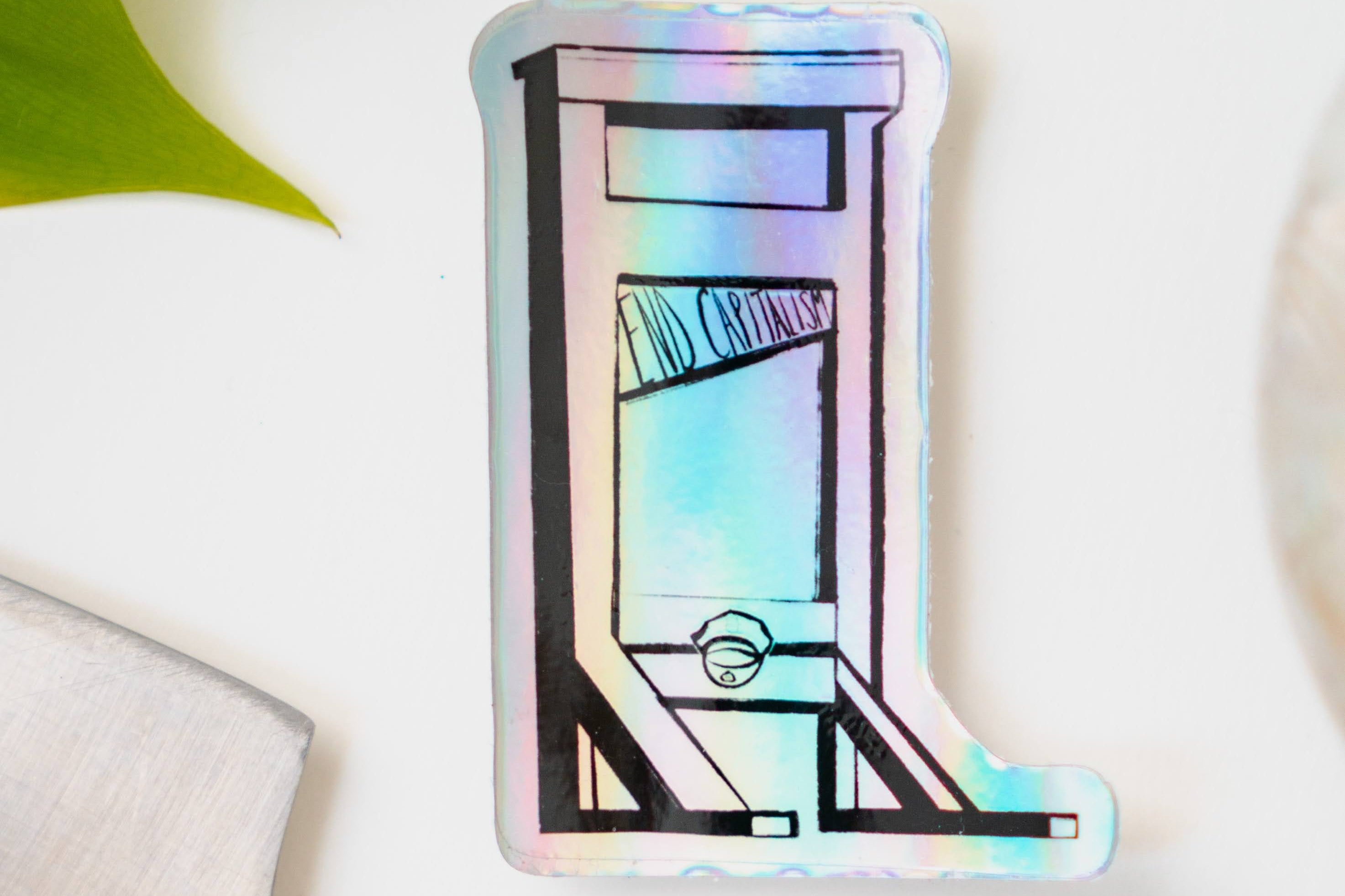 A holographic sticker of a guillotine, with the words "End Capitalism" written on the blade.