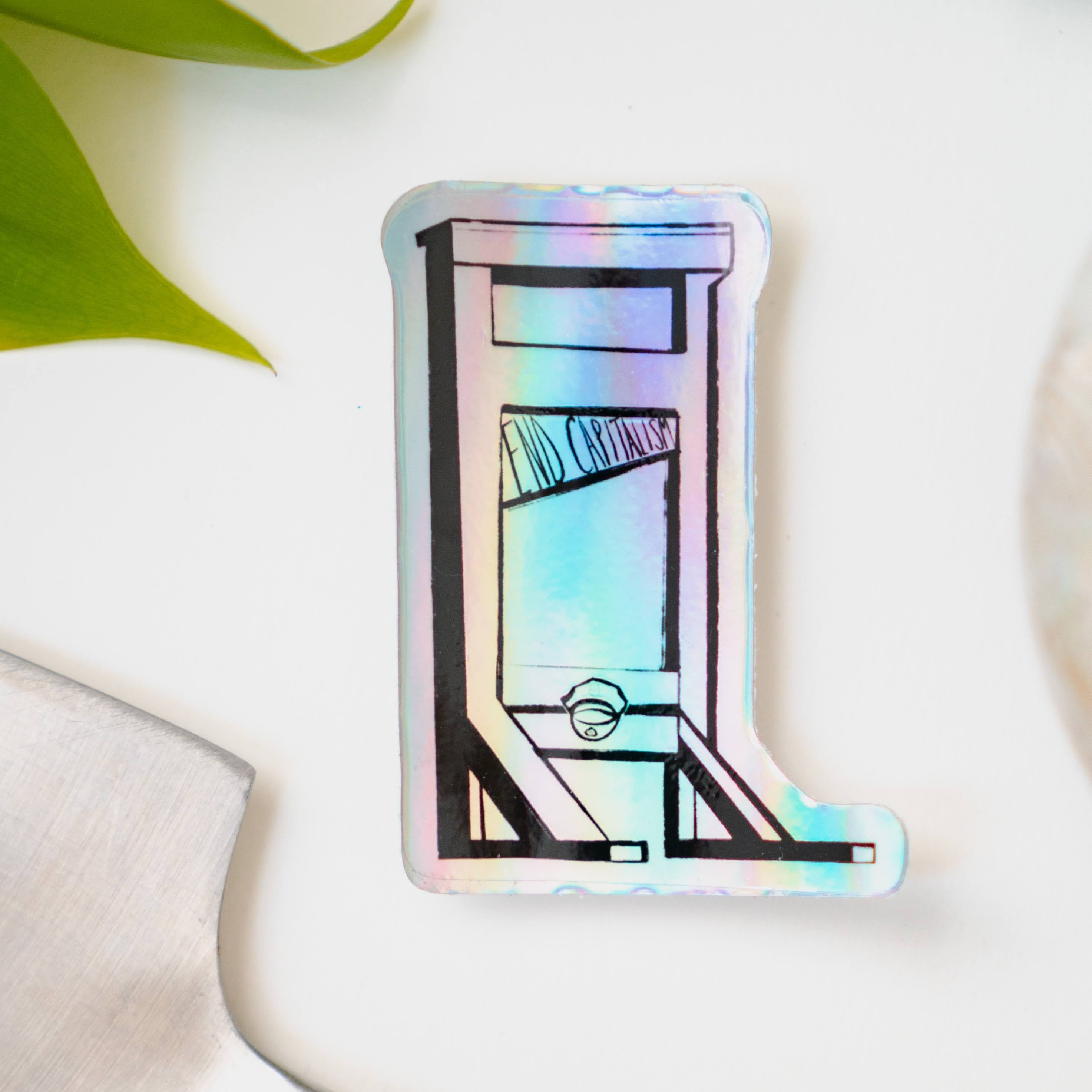 A holographic sticker of a guillotine, with the words "End Capitalism" written on the blade.