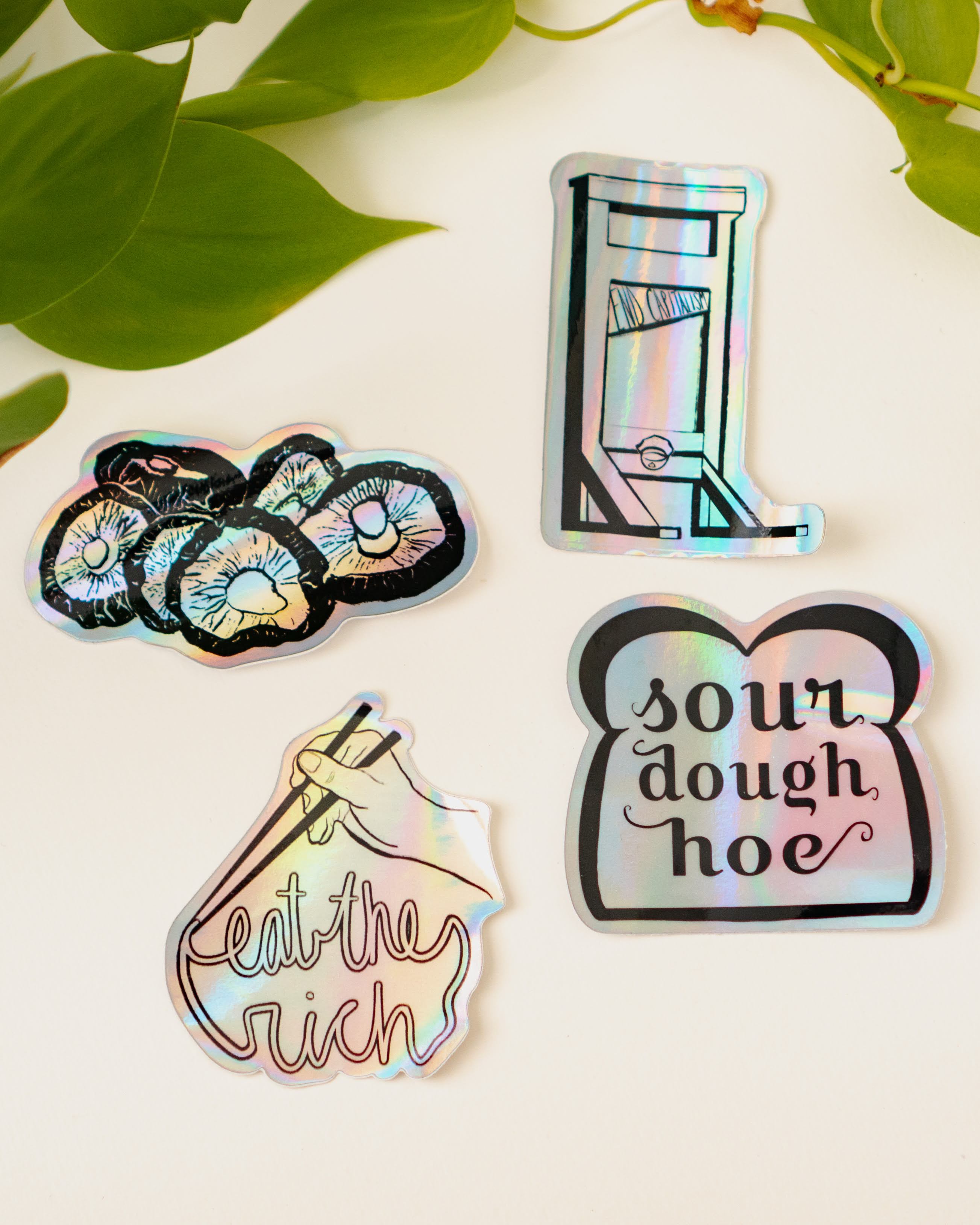 Menmin Made's collection of four holographic stickers, including the End Capitalism Guillotine Sticker.