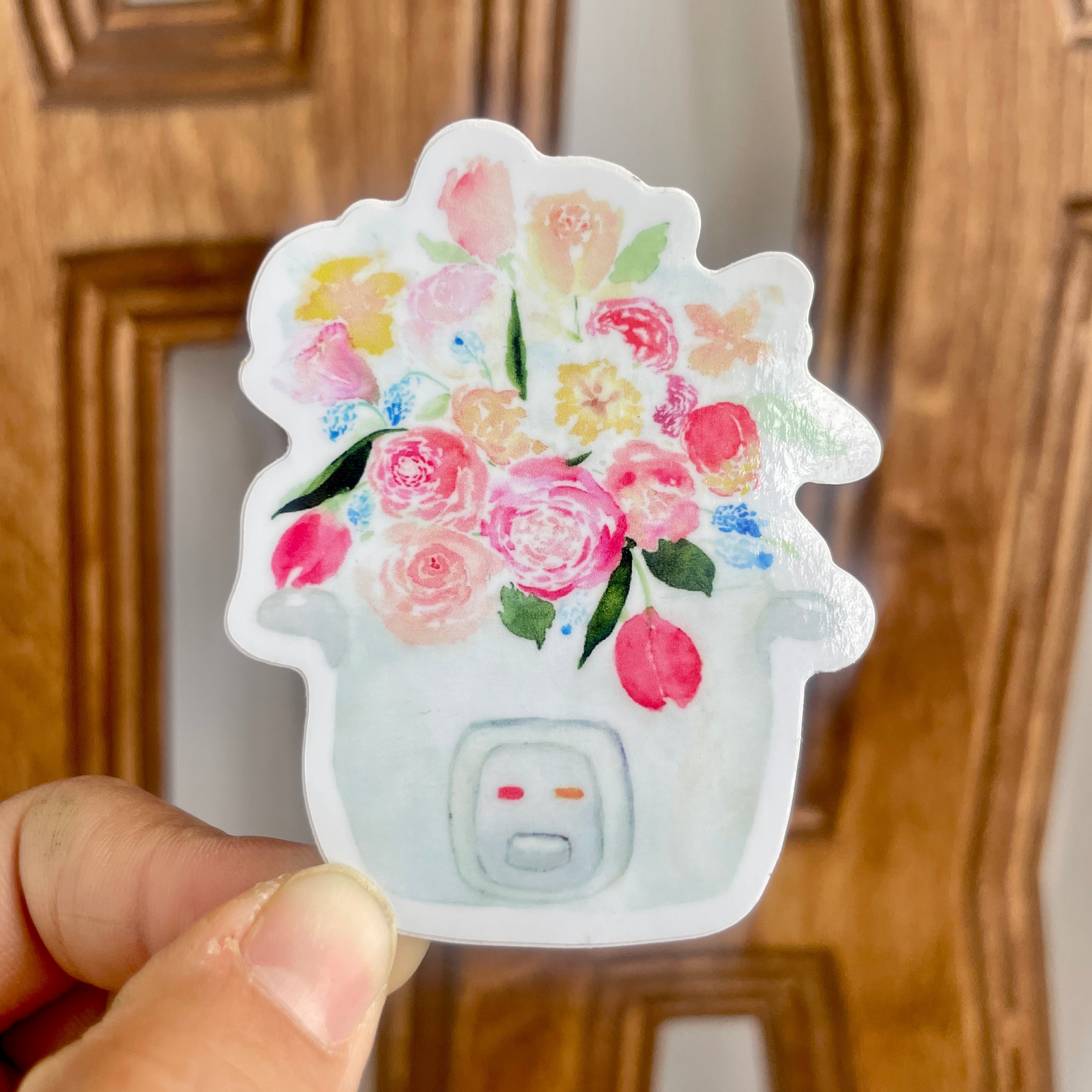 A pink, blue, and white sticker of a bouquet of tulips, roses, and other flowers sprouting out of a rice cooker.