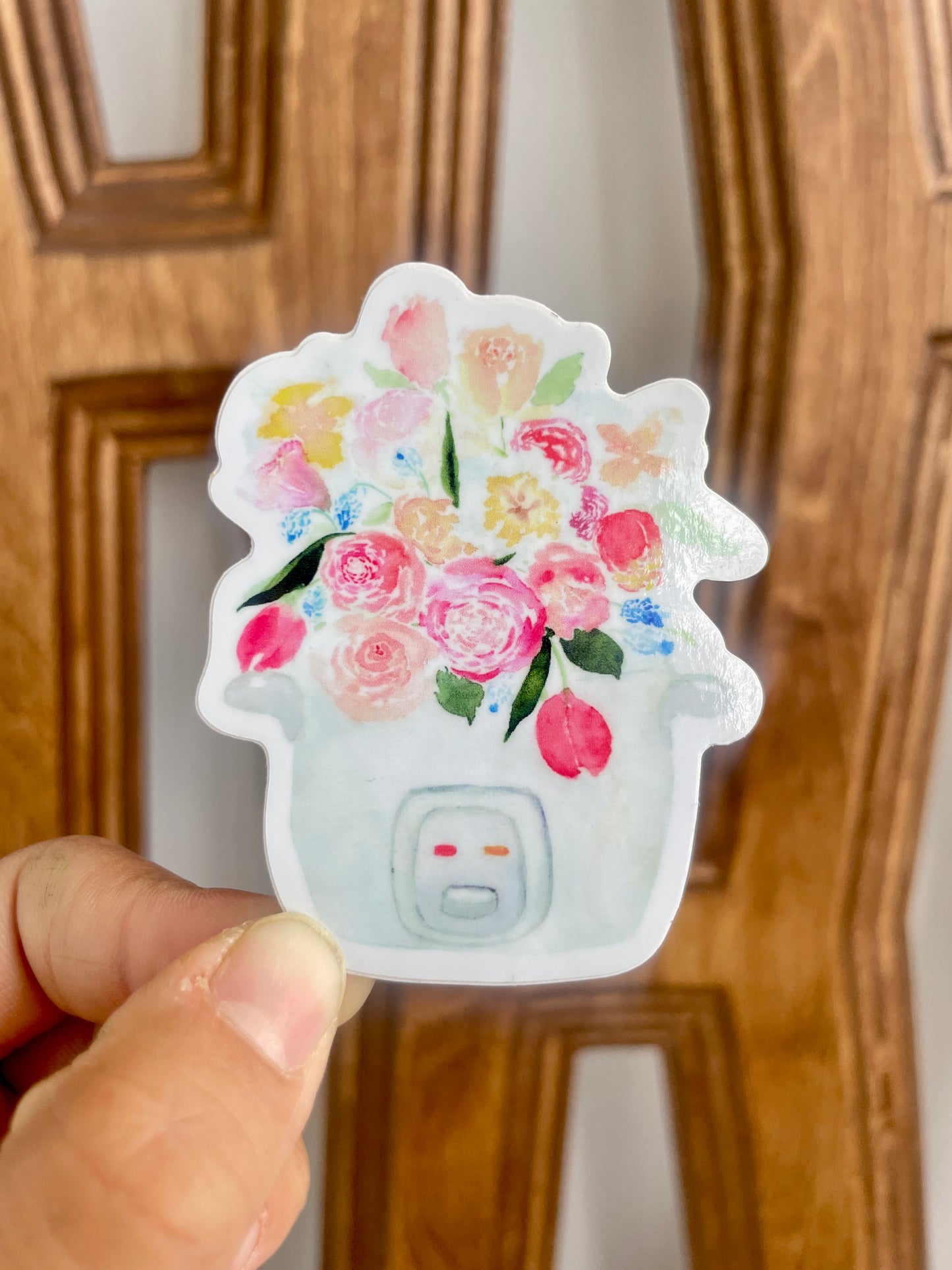 A pink, blue, and white sticker of a bouquet of tulips, roses, and other flowers sprouting out of a rice cooker.