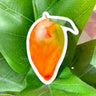 A sticker of a green and orange whole mango with a small green leaf still attached.