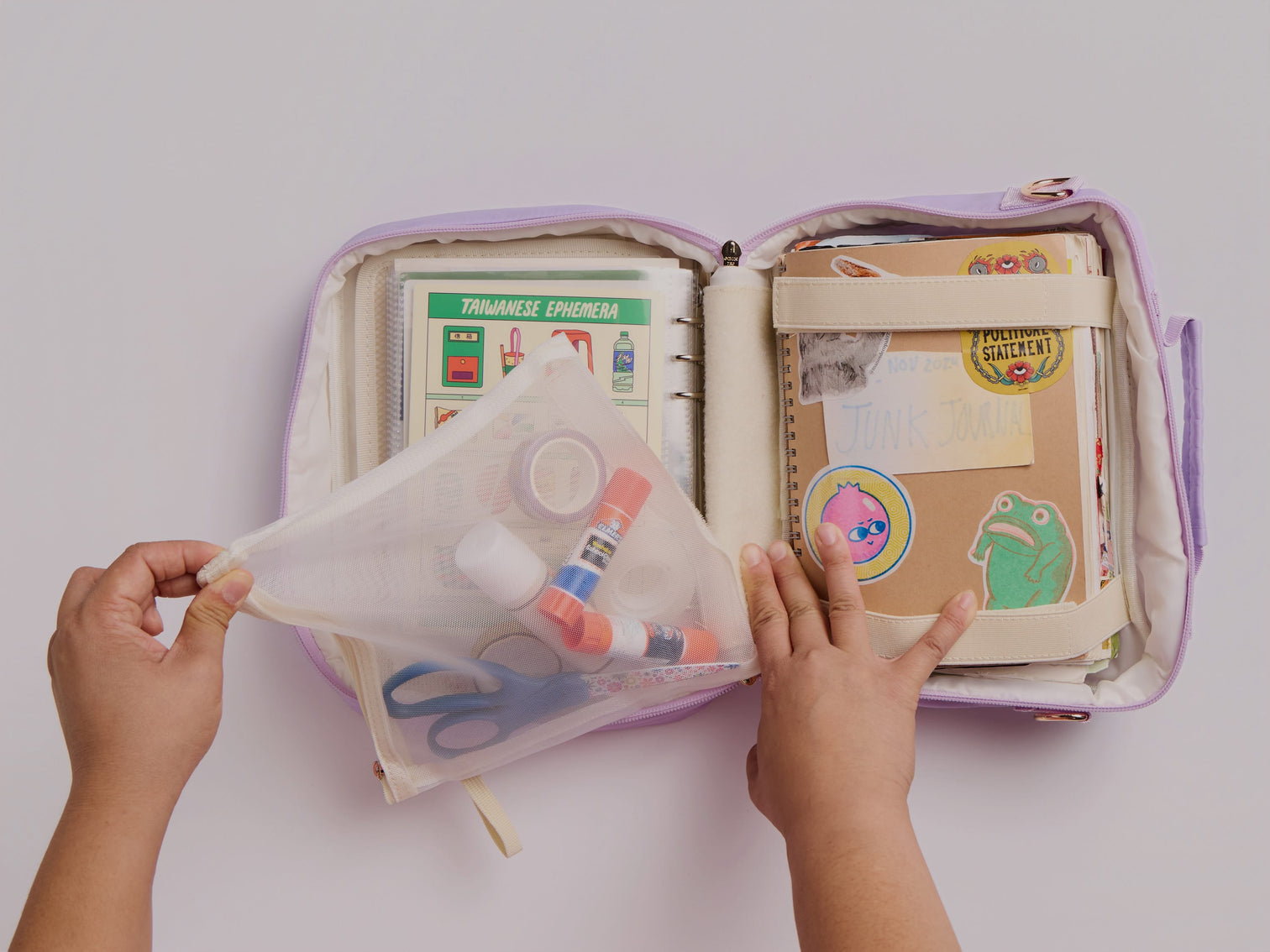Open purple pencil case with stationery items on a white background