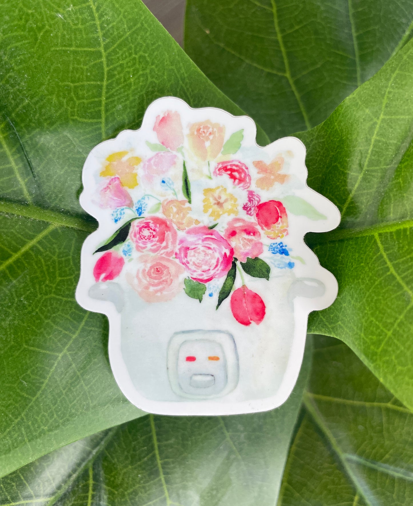 A pink, blue, and white sticker of a bouquet of tulips, roses, and other flowers sprouting out of a rice cooker.