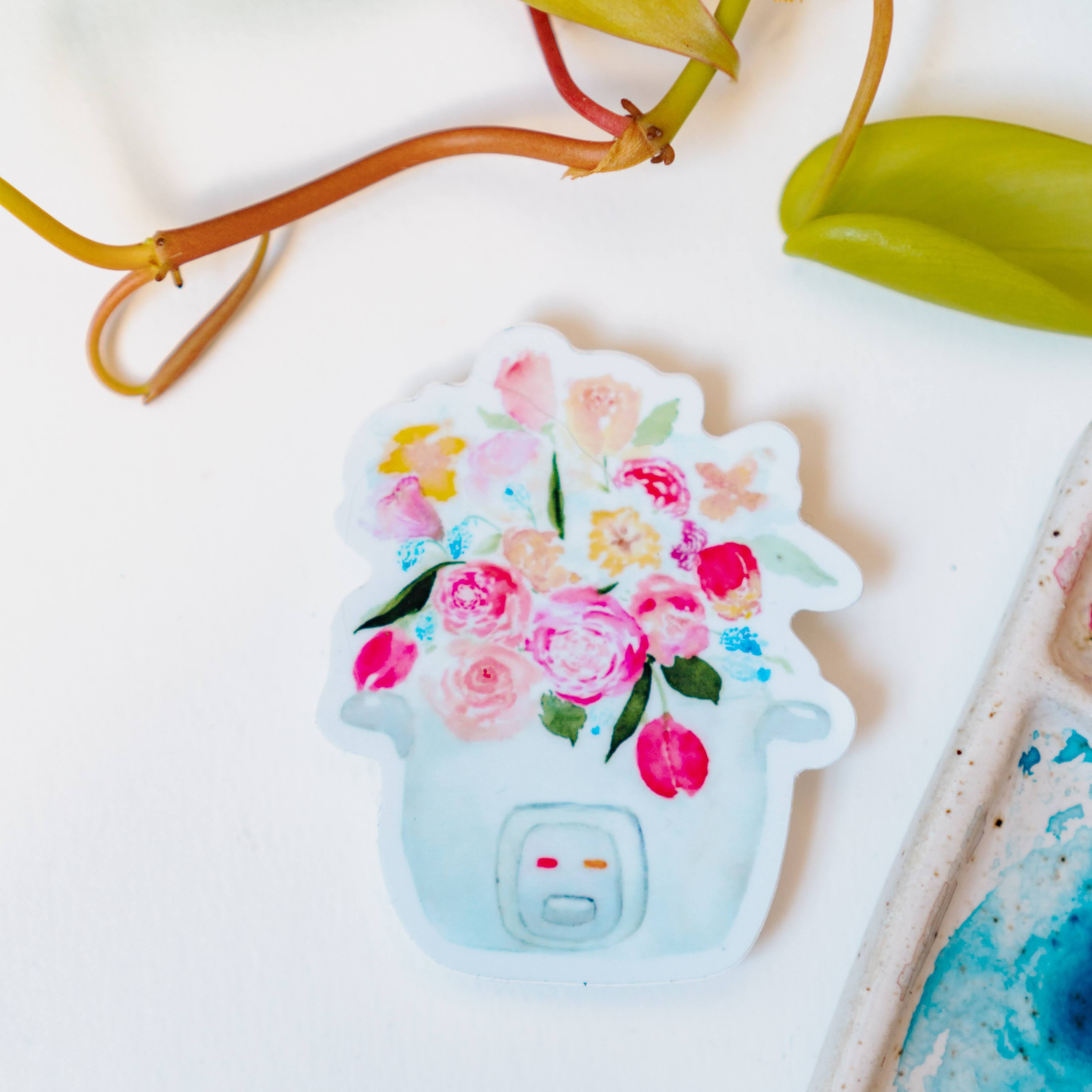 A pink, blue, and white sticker of a bouquet of tulips, roses, and other flowers sprouting out of a rice cooker.