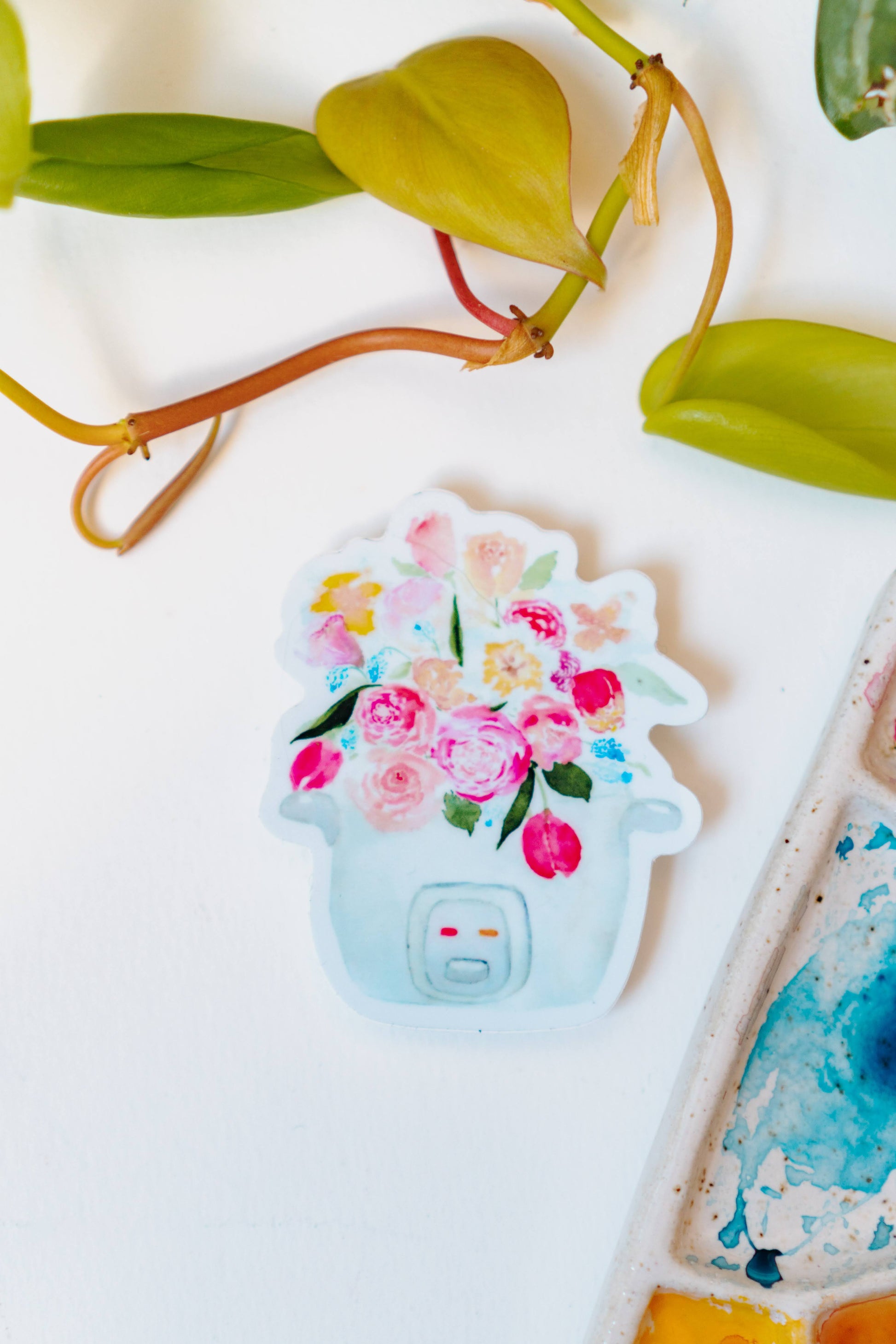 A pink, blue, and white sticker of a bouquet of tulips, roses, and other flowers sprouting out of a rice cooker.